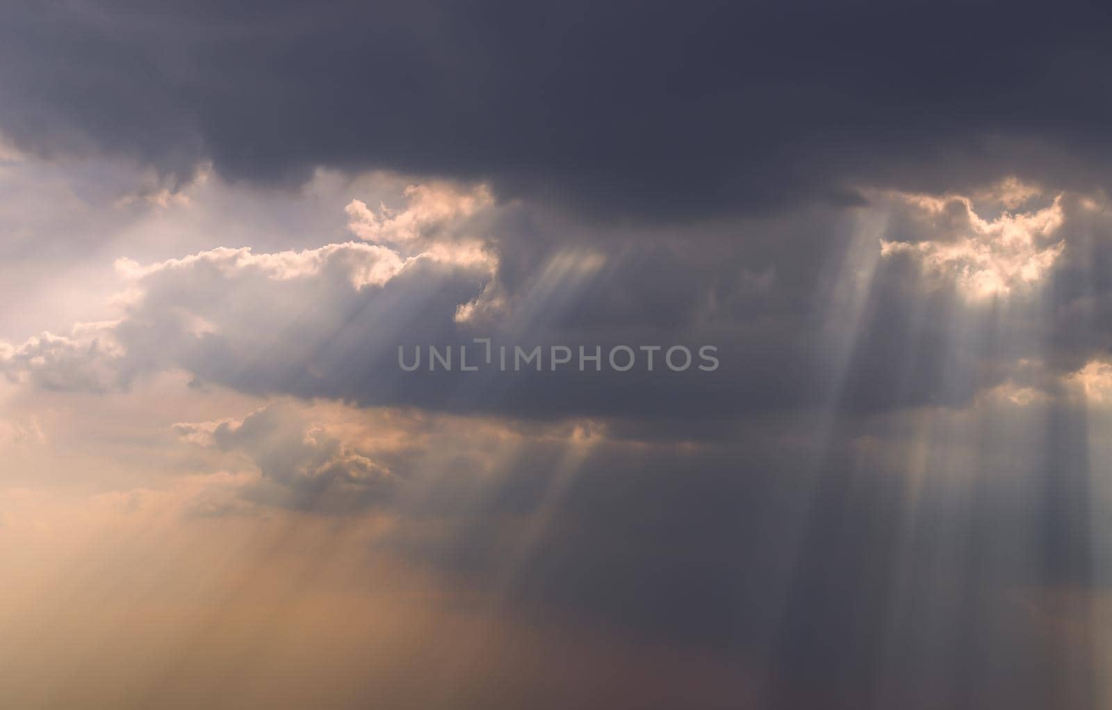 The sun's rays passing through the clouds and shining form an interesting light pattern against the sky. Copy space. Selective focus.