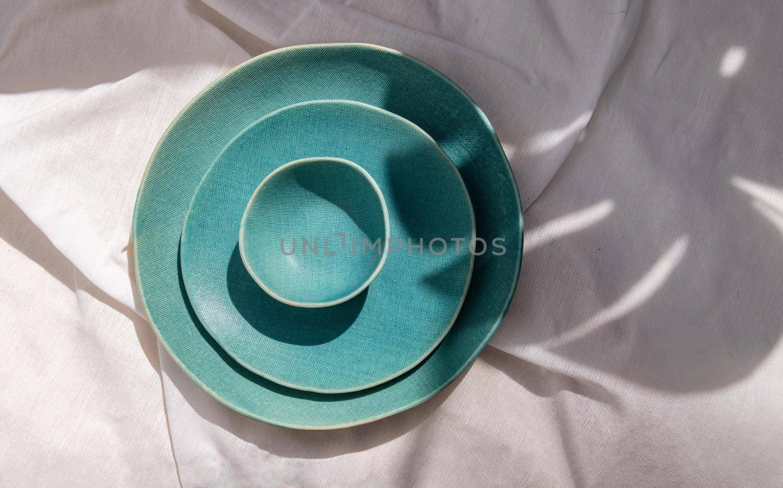 Set of Ceramic Plates on white textured table cloth. Ceramic tableware, Beautiful arrangement, Space for text.