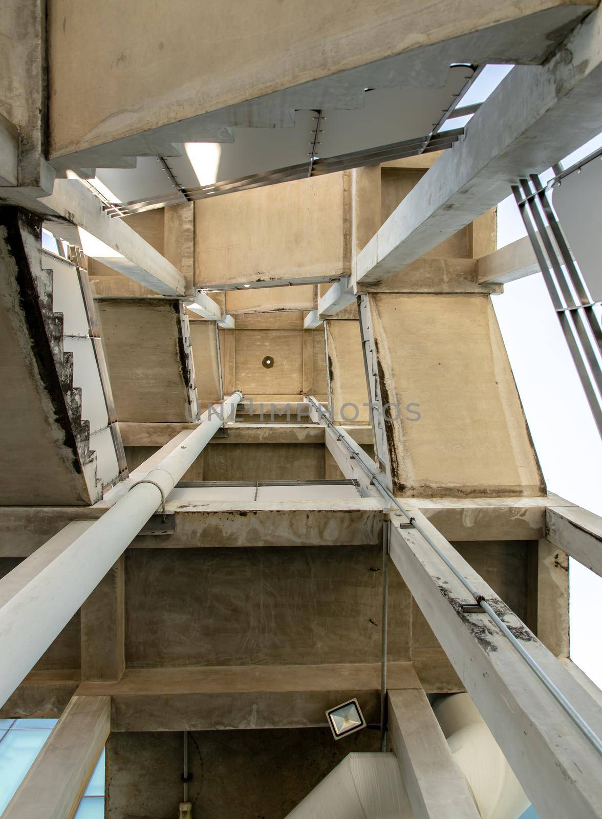 Looking up at Emergency fire escape staircase on the back side of a high concrete building. Fire safety. The geometry of the building, No focus, specifically.