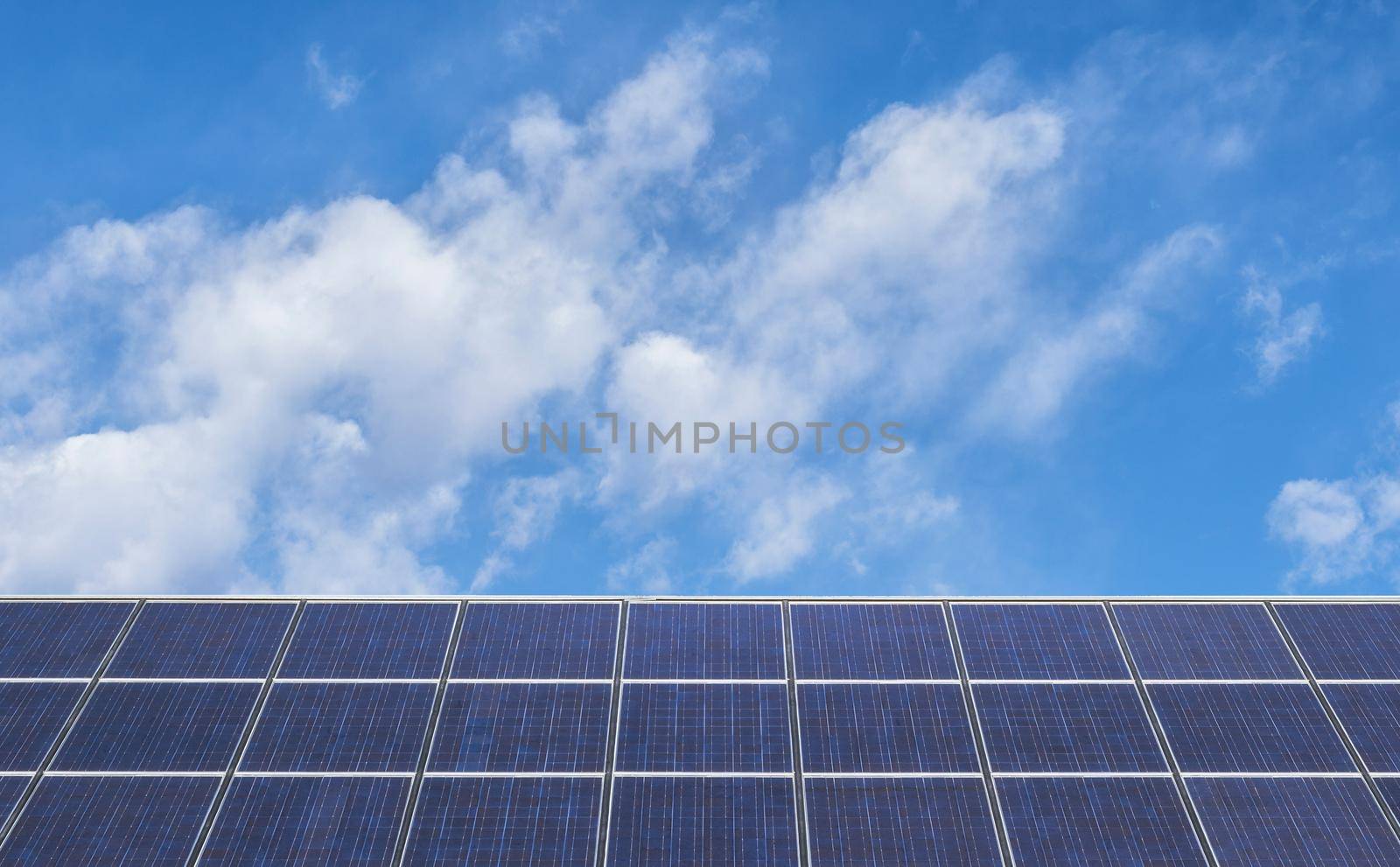 Solar Panels Against Blue Sky and fluffy white clouds.