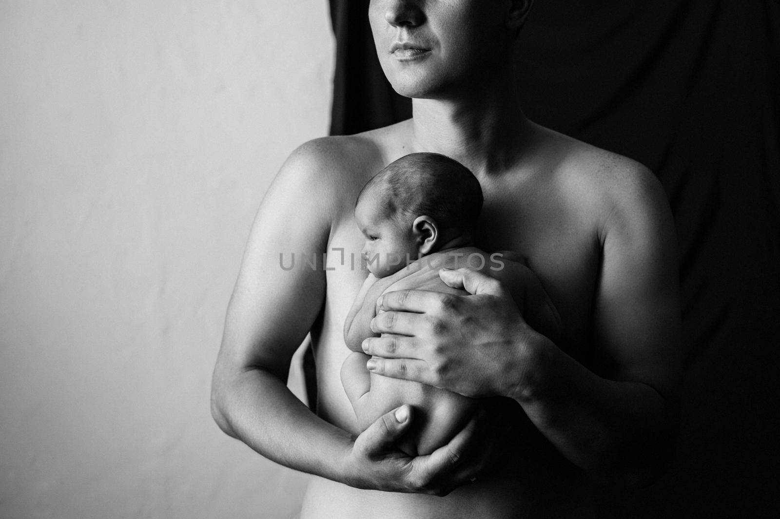 Father holding his newborn son on a black background. High quality photo