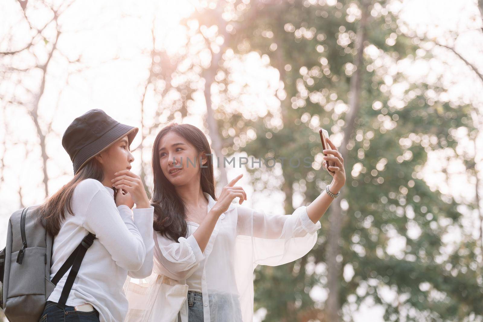 Two young attractive asian girls take a selfie at the park.