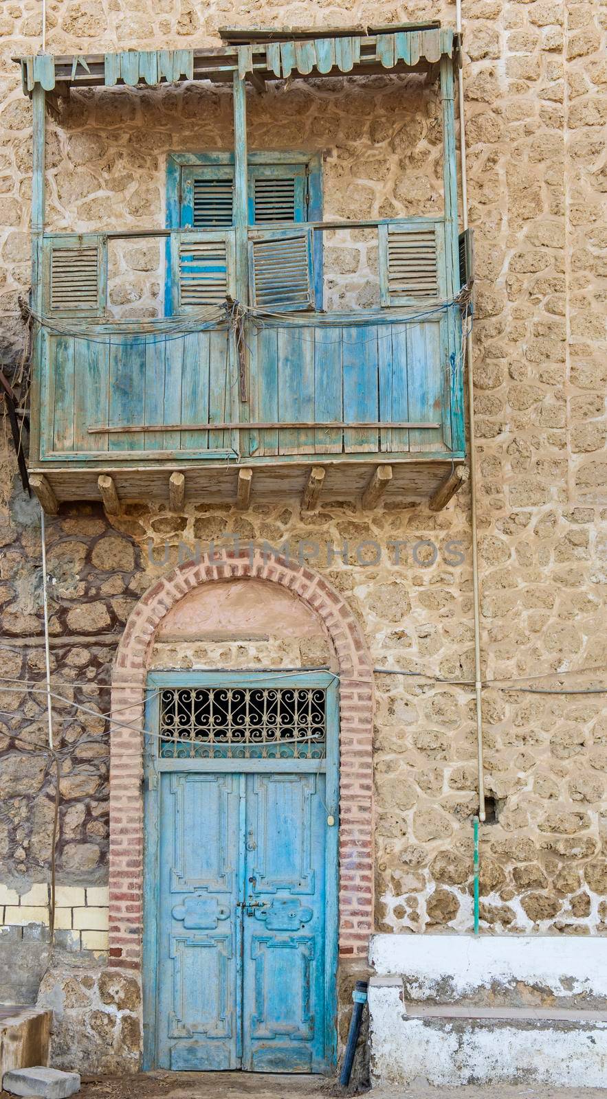 Old rustic wooden doors and balcony on wall of abandoned traditional egyptian house