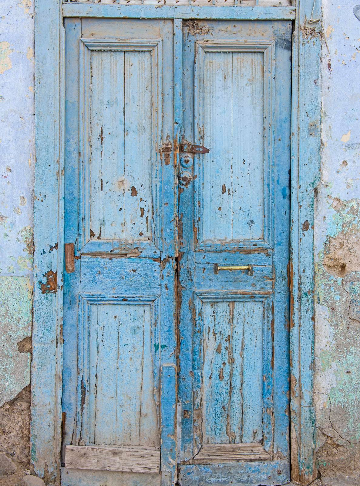 Old rustic wooden door in wall of abandoned traditional egyptian house