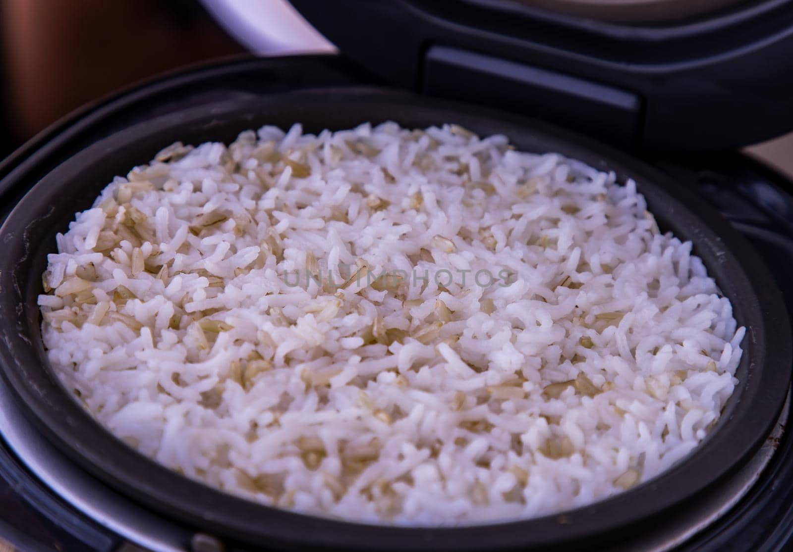 Jasmine rice Cooking mixed with Coarse brown rice (milled rice imperfectly cleaned, unpolished or half milled rice) in electric rice cooker with steam. Healthy food and diet concept. Selective focus.
