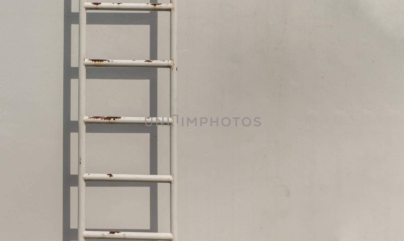 White metal fire escape attached to a wall and leading to the roof of a building. Copy space, Selective focus.