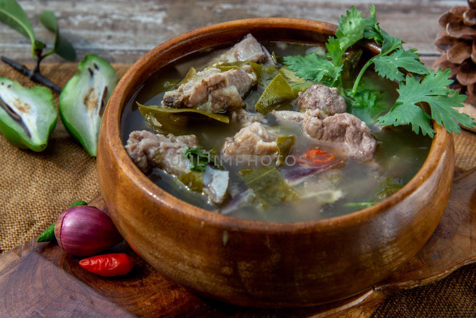 Pork spare rip Madan soup (Kra Dook Moo Tom Ma-Dun) in a wooden bowl, Traditional Thai food, Oblique view from the top.