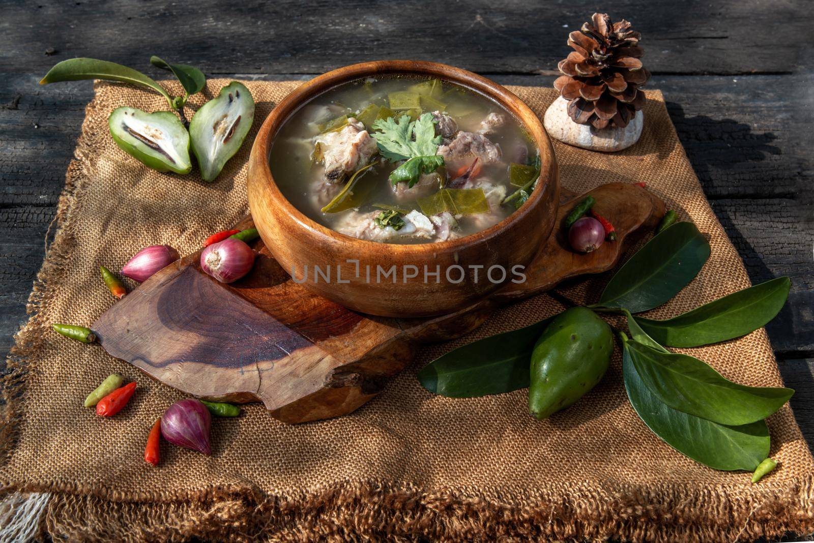 Pork spare rip Madan soup (Kra Dook Moo Tom Ma-Dun) in a wooden bowl, Traditional Thai food, Oblique view from the top.