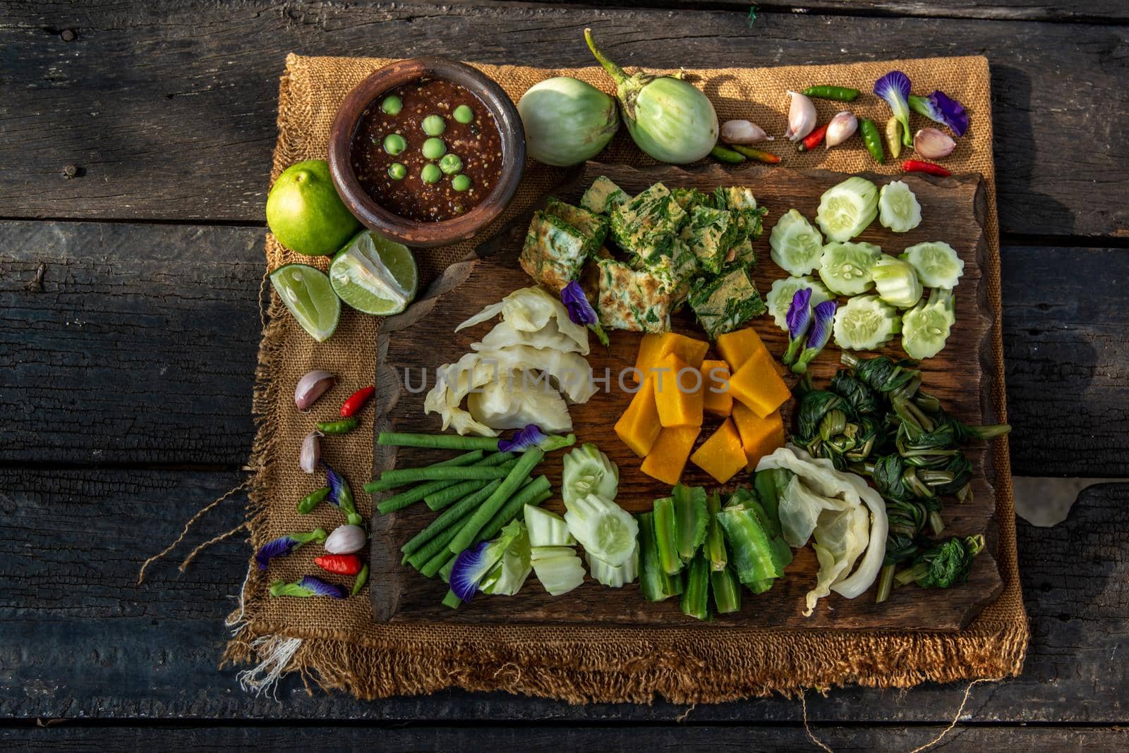 Thai Traditional Local Food : Spicy Shrimp Paste Dip or Fried shrimp paste sauce (Nam Prik Kapi) with blanched vegetables and cha-om omelets on wooden backgroud.