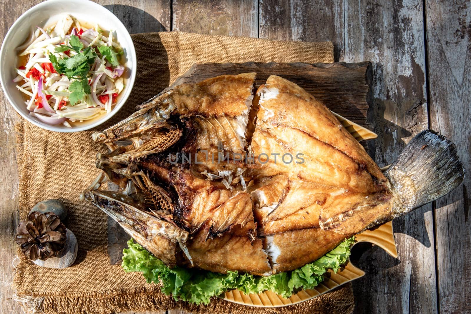 Deep fried Snapper with fish sauce on vintage wooden, The perfect frying process, Set hot fire, then bring the snapper to fry to frame and topped with fish sauce.