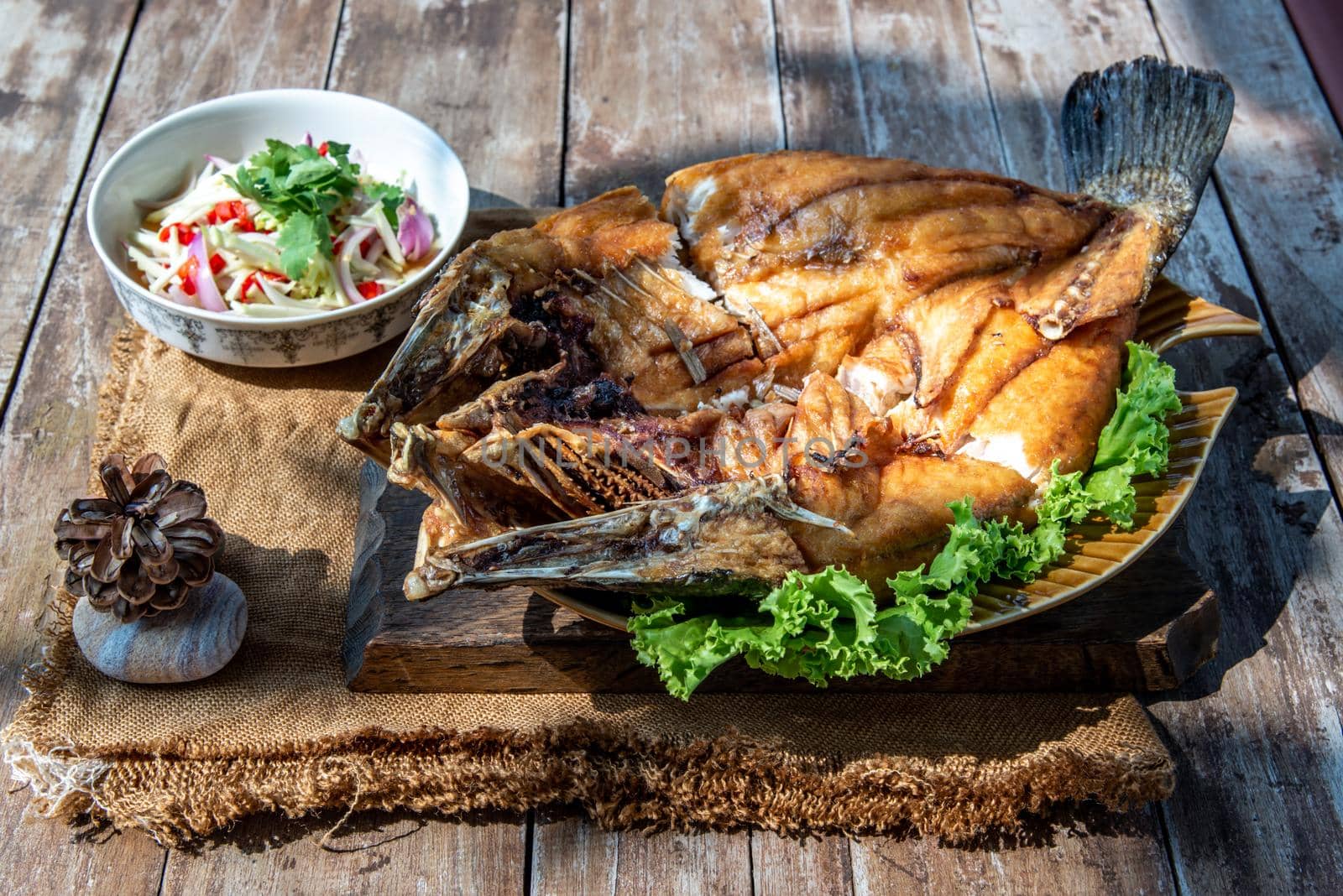 Deep fried Snapper with fish sauce on vintage wooden, The perfect frying process, Set hot fire, then bring the snapper to fry to frame and topped with fish sauce.