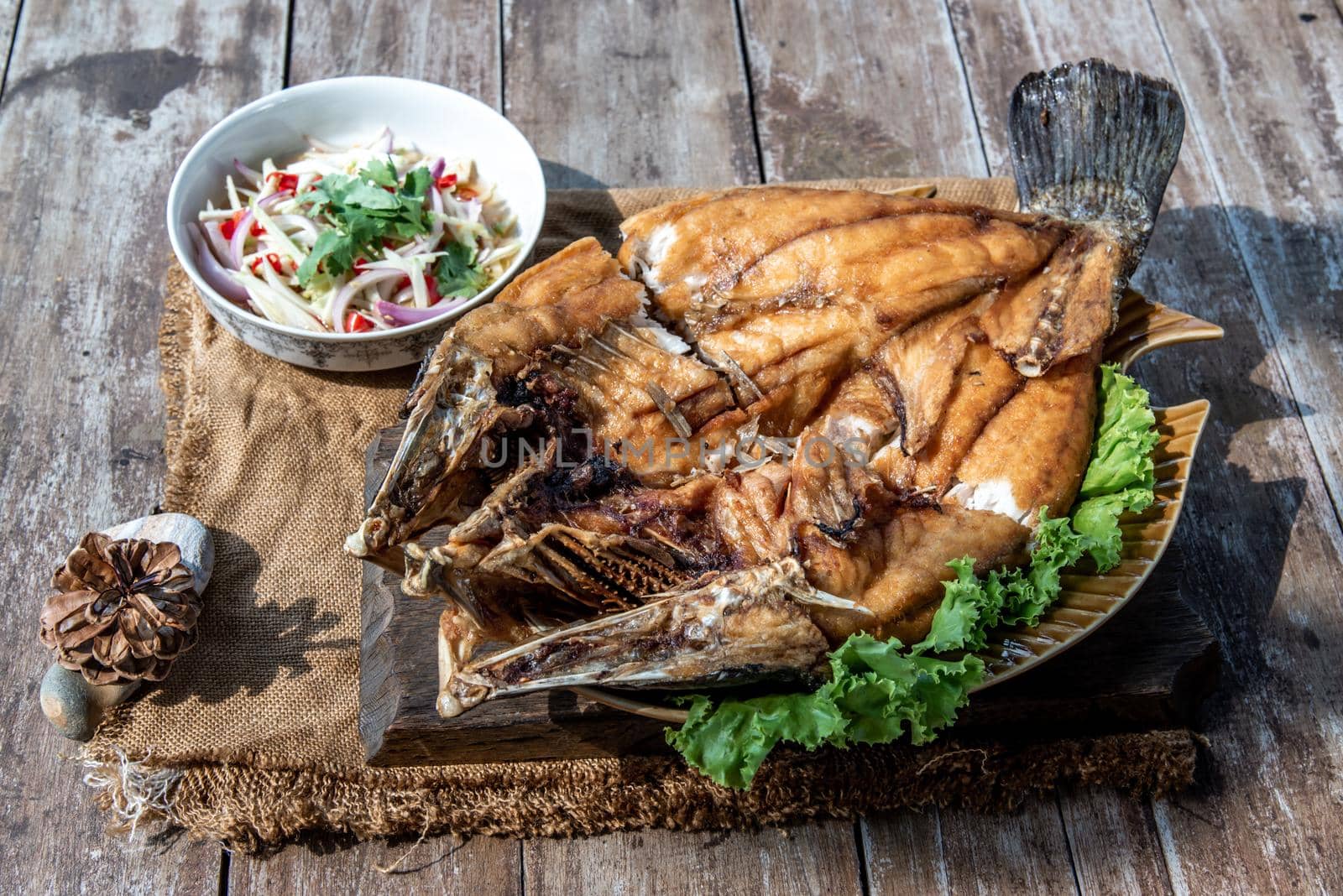 Deep fried Snapper with fish sauce on vintage wooden, The perfect frying process, Set hot fire, then bring the snapper to fry to frame and topped with fish sauce.