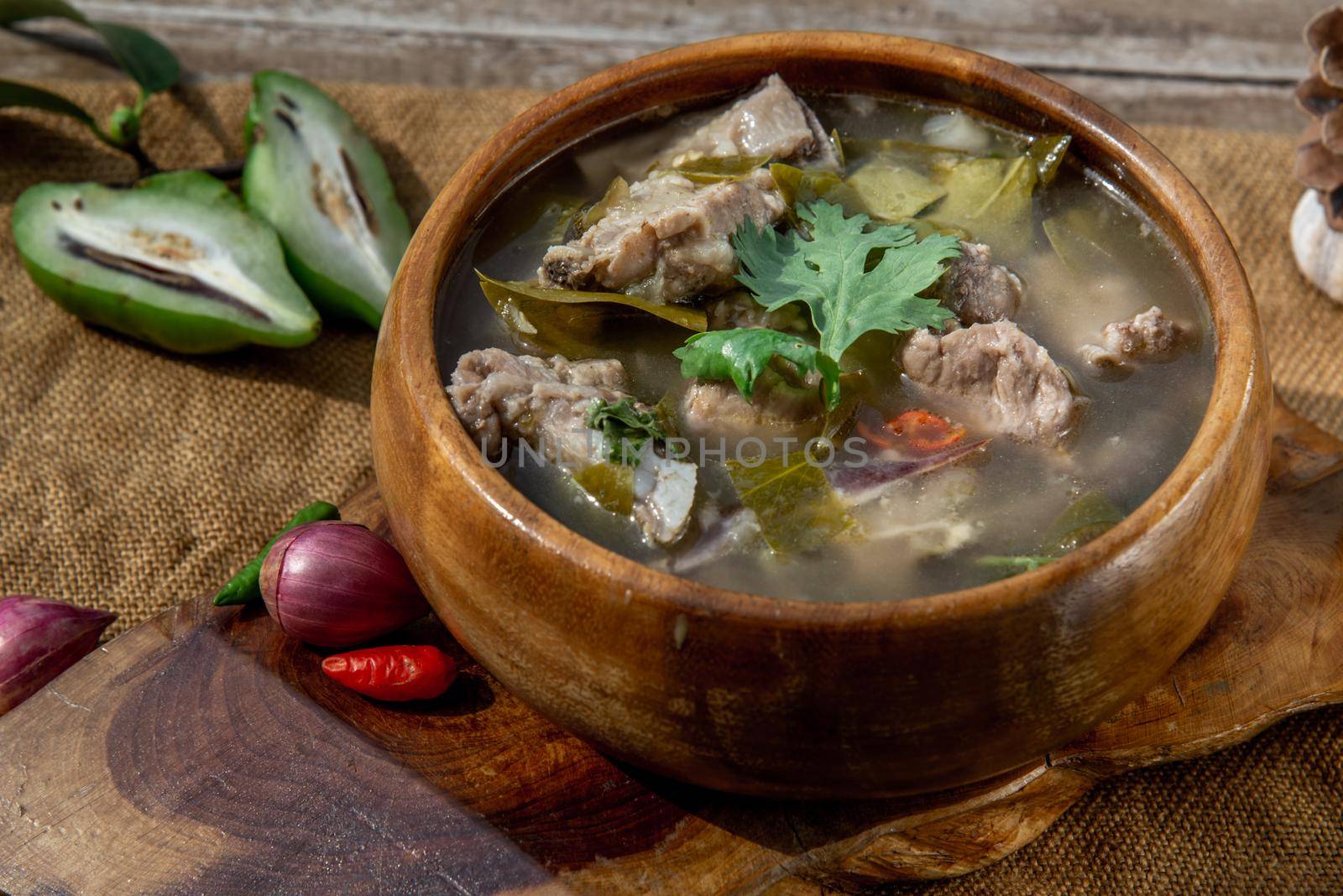 Pork spare rip Madan soup (Kra Dook Moo Tom Ma-Dun) in a wooden bowl, Traditional Thai food, Oblique view from the top.