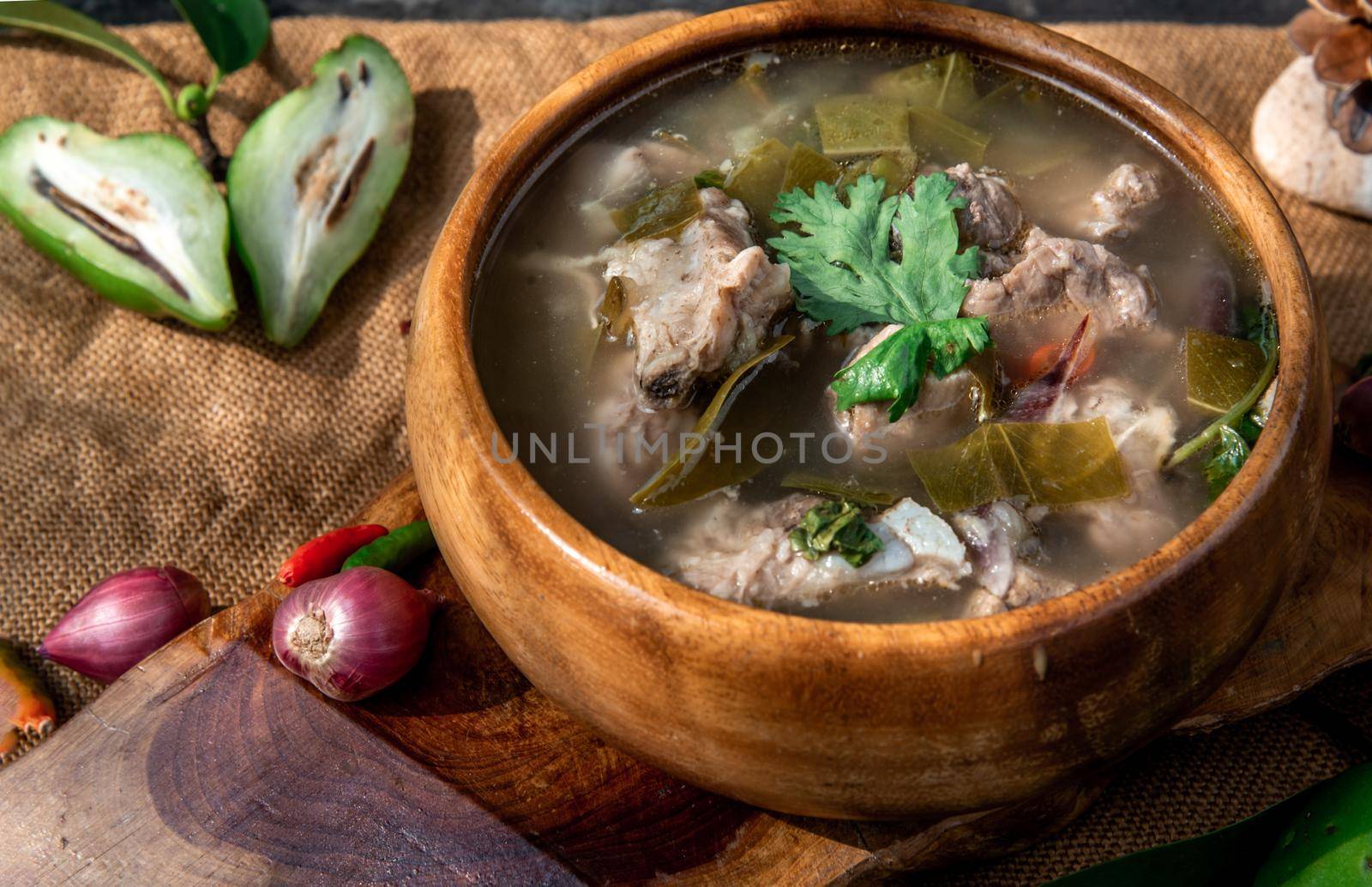 Pork spare rip Madan soup (Kra Dook Moo Tom Ma-Dun) in a wooden bowl, Traditional Thai food, Oblique view from the top.