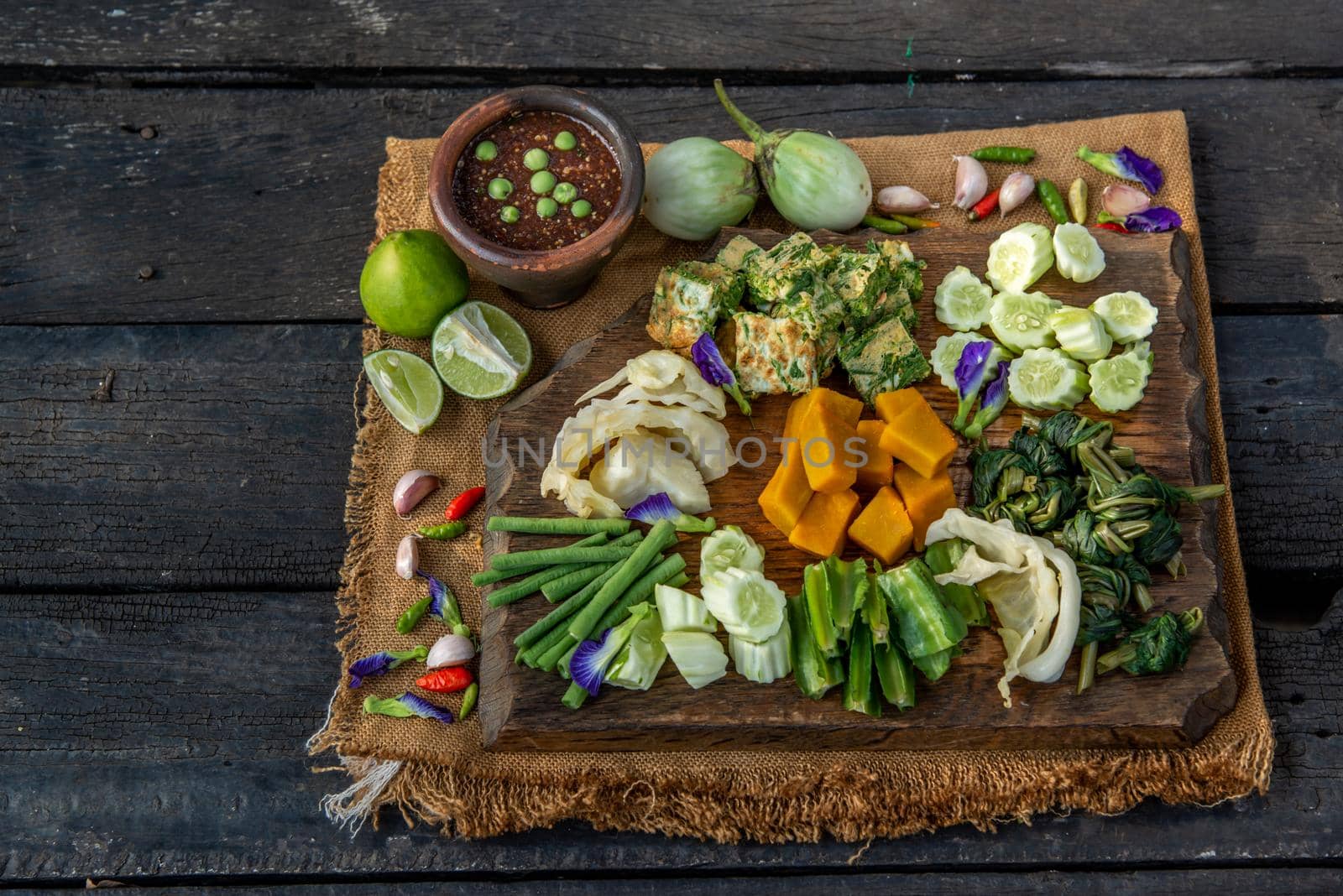 Thai Traditional Local Food : Spicy Shrimp Paste Dip or Fried shrimp paste sauce (Nam Prik Kapi) with blanched vegetables and cha-om omelets on wooden backgroud.