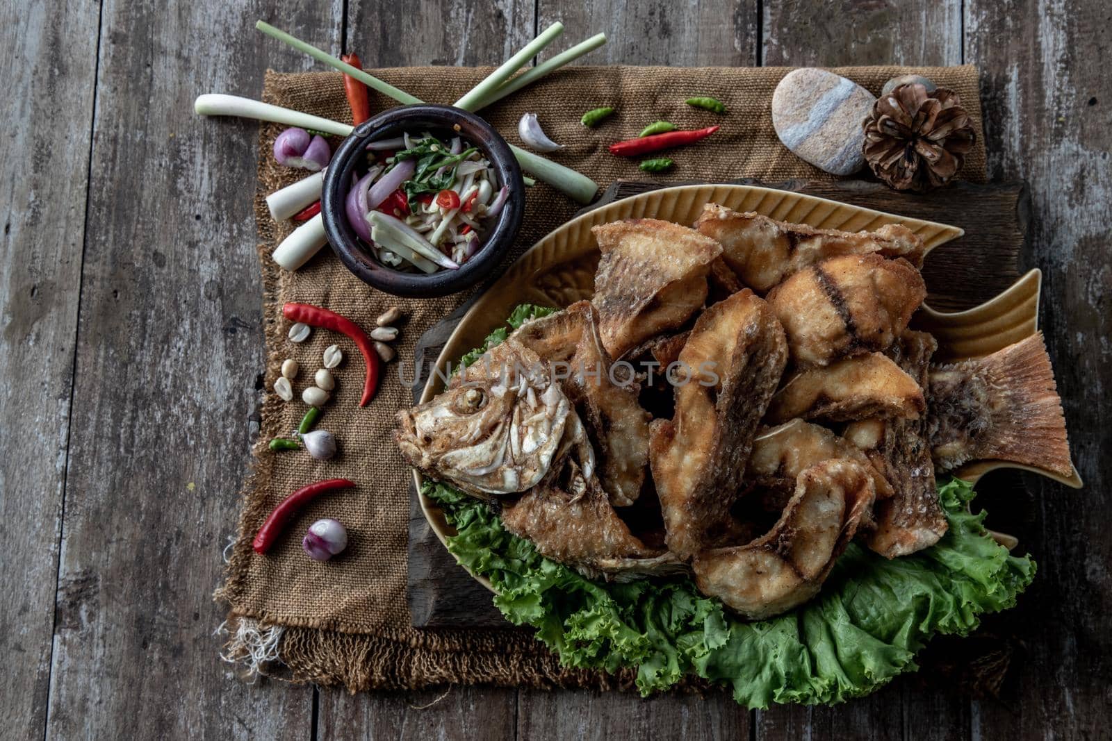 Deep fried Tubtim fish with fish sauce on vintage wooden, The perfect frying process, Set hot fire, then bring the Tubtim fish to fry to frame and topped with fish sauce.