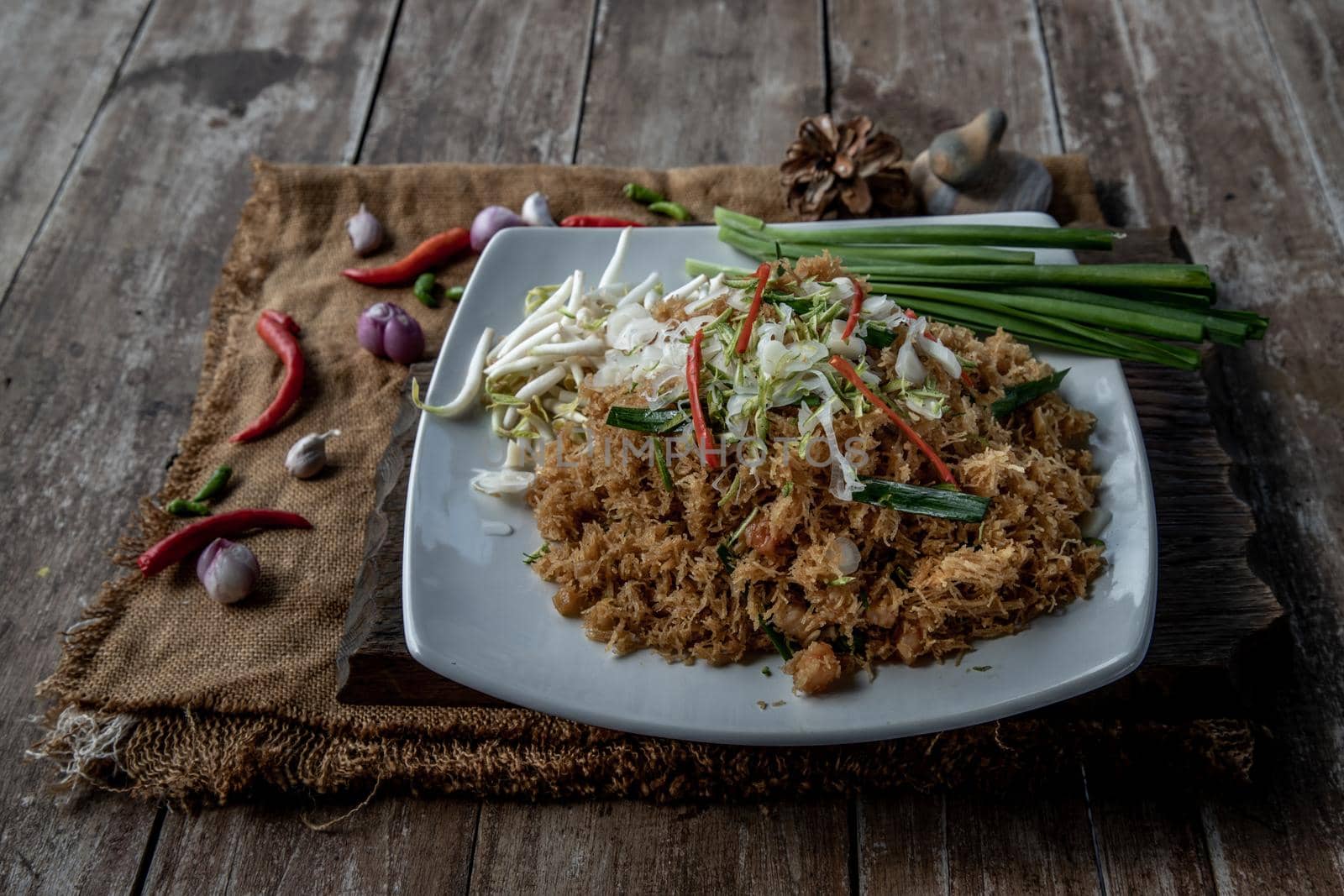 Asian eating food, Mee Grob is an sweet and sour crispy noodles, made from Thai rice noodle with sweet and sour sauce on white plate, Sweet & Sour Crispy Rice Noodles, Oblique view from the top.