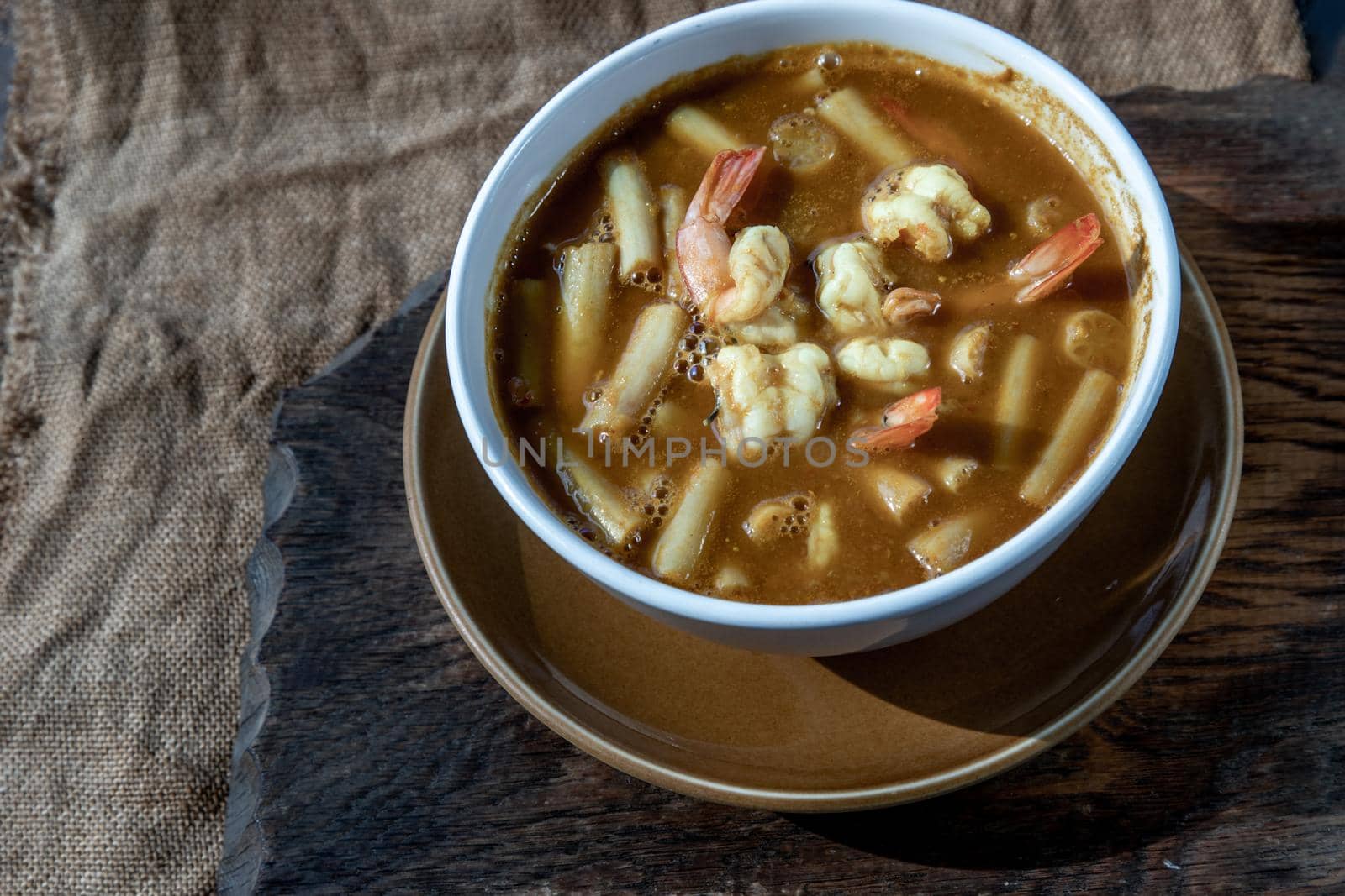 Sour soup with lotus stem and shrimps (kaeng som koong with lotus stem), Traditional Thai food, Oblique view from the top.