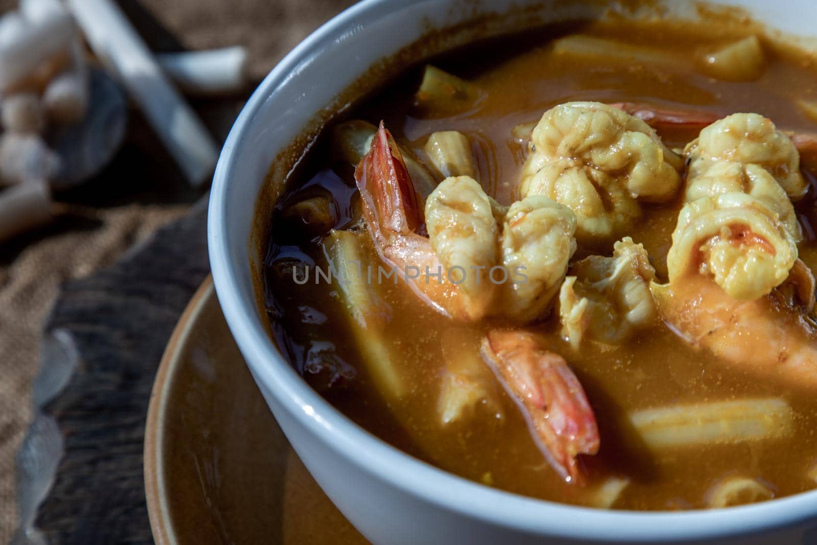 Close-up of Sour soup with lotus stem and shrimps (kaeng som koong with lotus stem), Traditional Thai food.