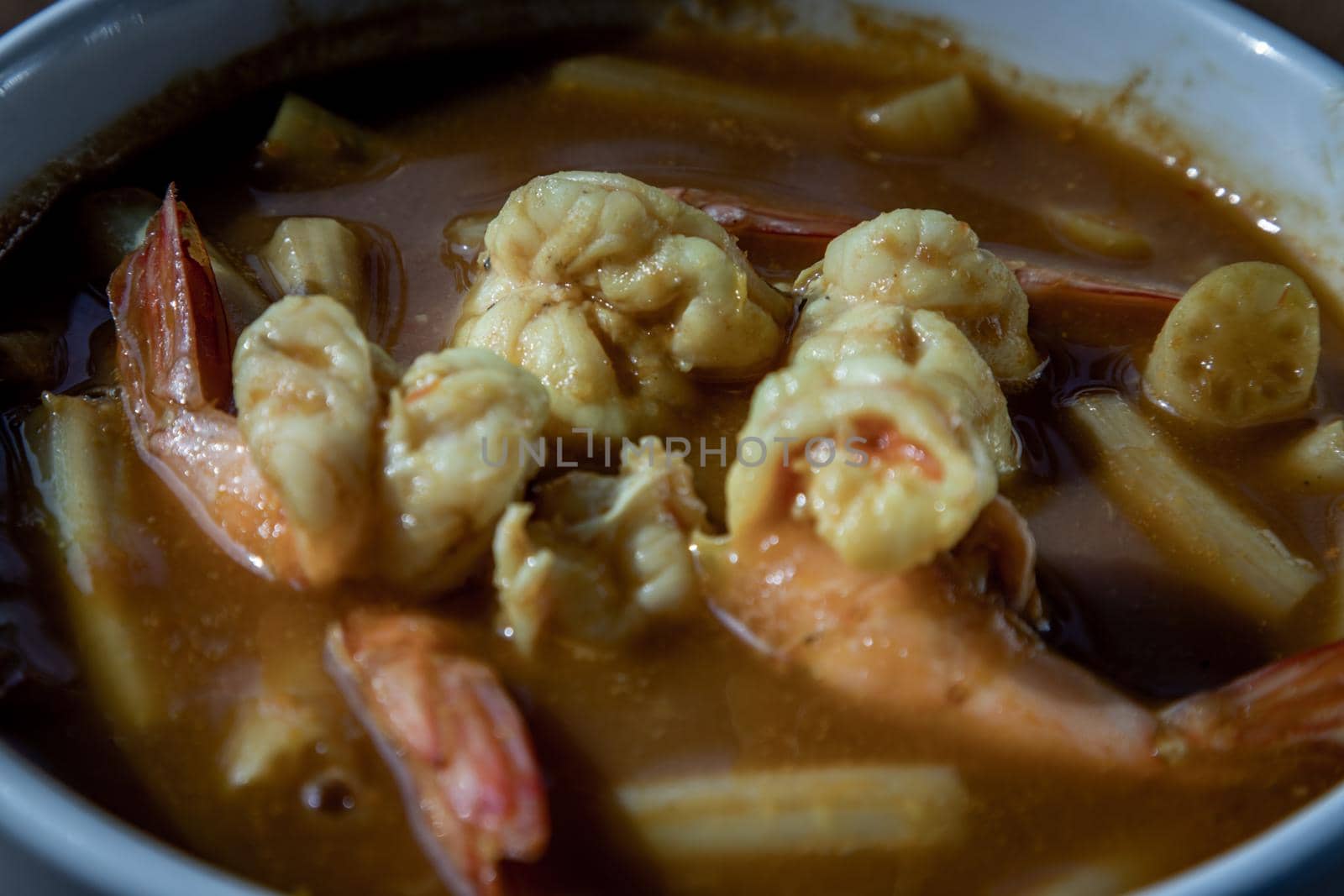 Close-up of Sour soup with lotus stem and shrimps (kaeng som koong with lotus stem), Traditional Thai food.