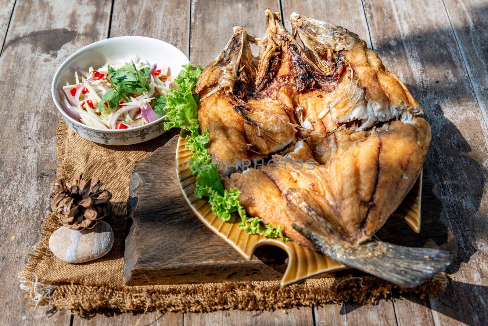 Deep fried Snapper with fish sauce on vintage wooden, The perfect frying process, Set hot fire, then bring the snapper to fry to frame and topped with fish sauce.