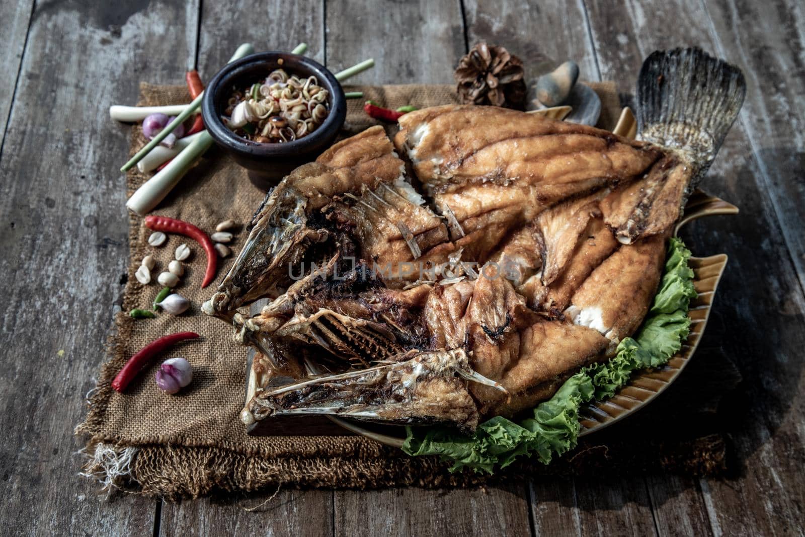 Deep fried Snapper with fish sauce on vintage wooden, The perfect frying process, Set hot fire, then bring the snapper to fry to frame and topped with fish sauce.