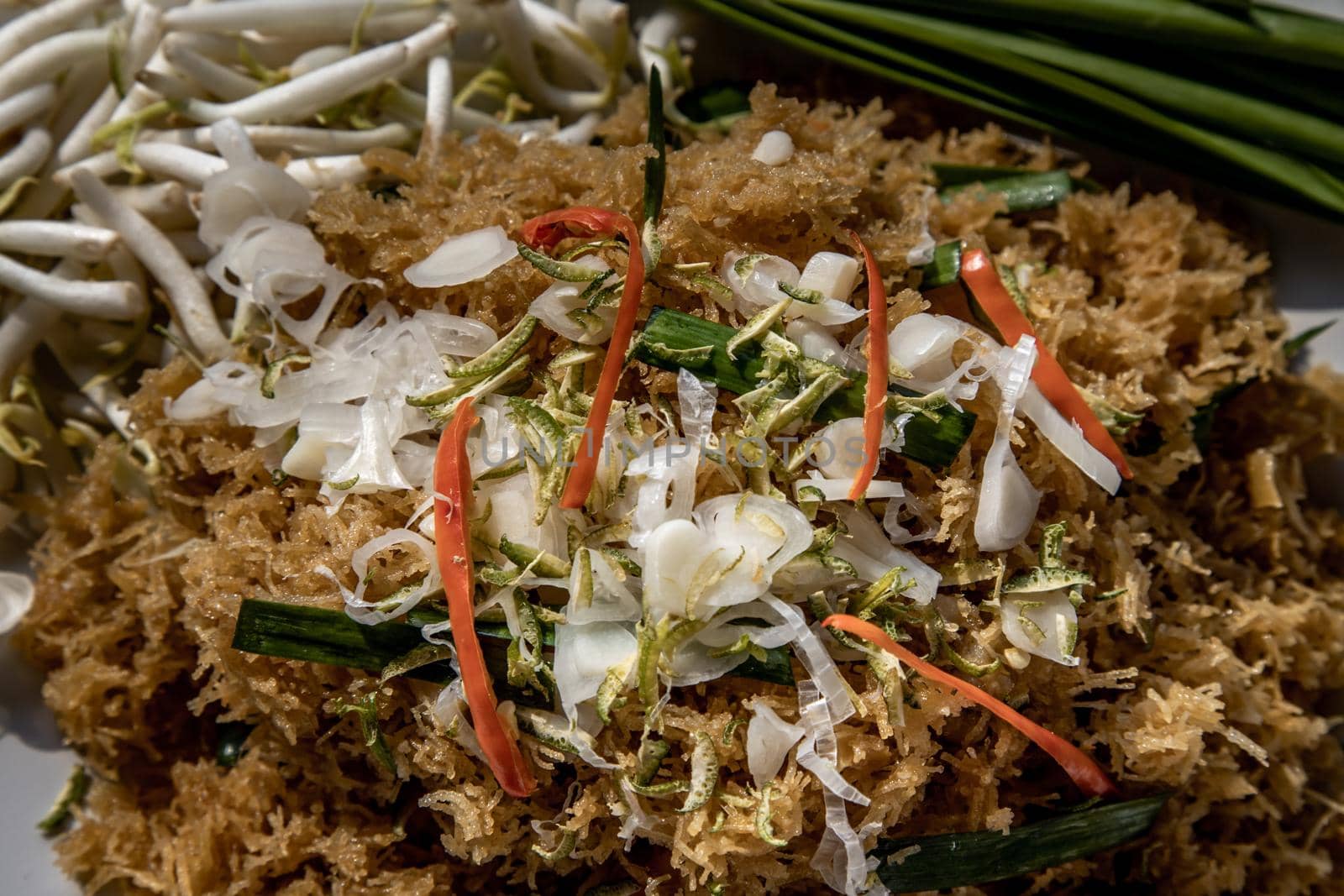 Asian eating food, Close-up of Mee Grob is an sweet and sour crispy noodles, made from Thai rice noodle with sweet and sour sauce on white plate, Sweet & Sour Crispy Rice Noodles.