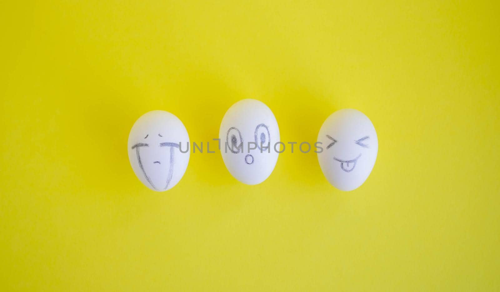White eggs with funny faces on a yellow background. Easter Concept.