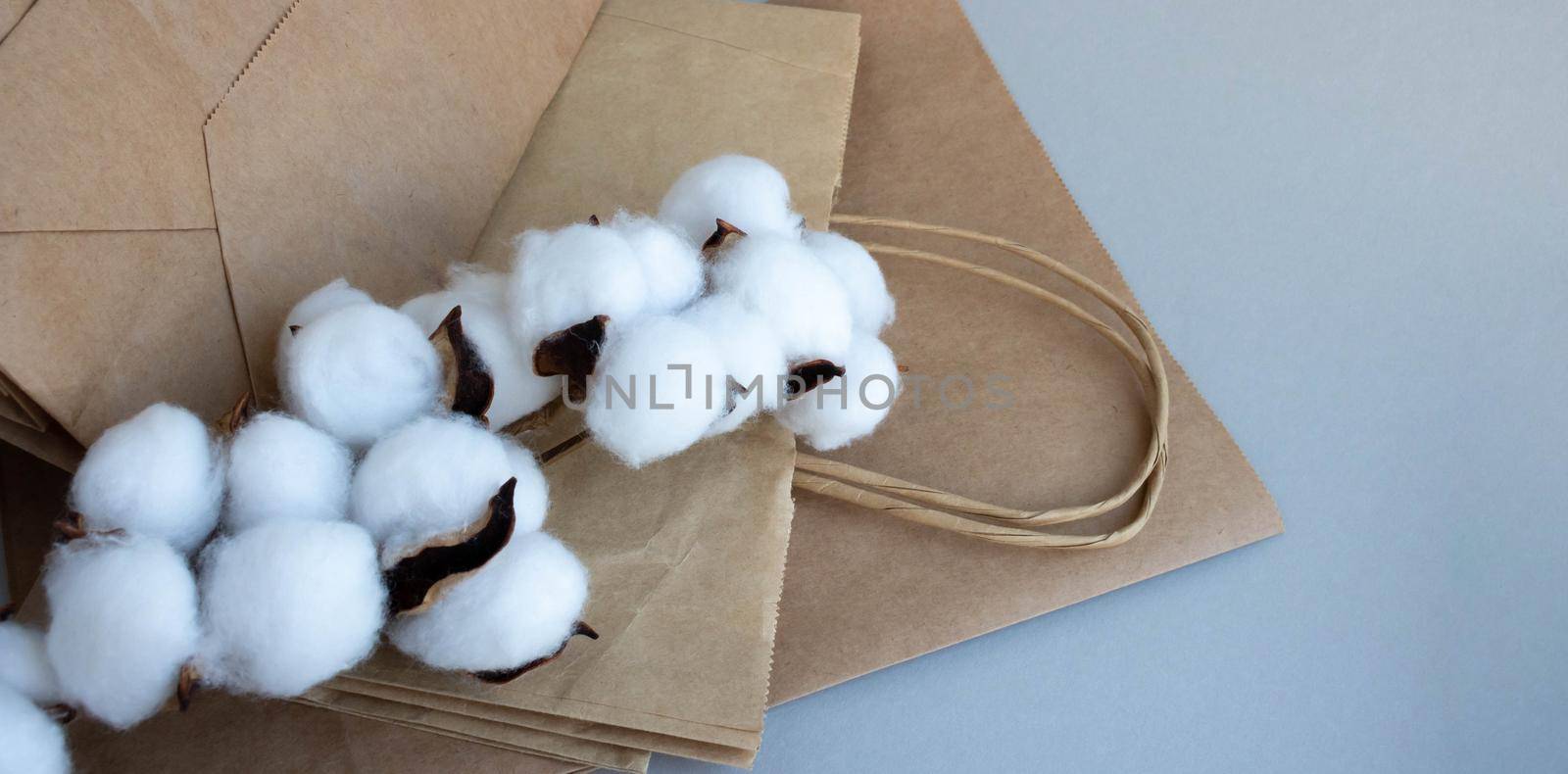 Organic eco-friendly paper bag with cotton flowers on a gray background. Zero waste and eco-friendly concept.