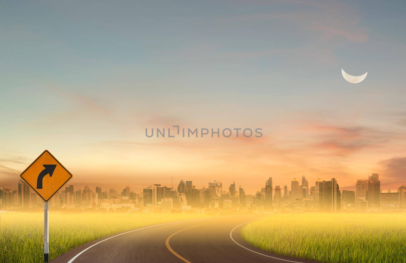 Sign curved road on the way at the natural sunset over field or meadow with moon and city background.