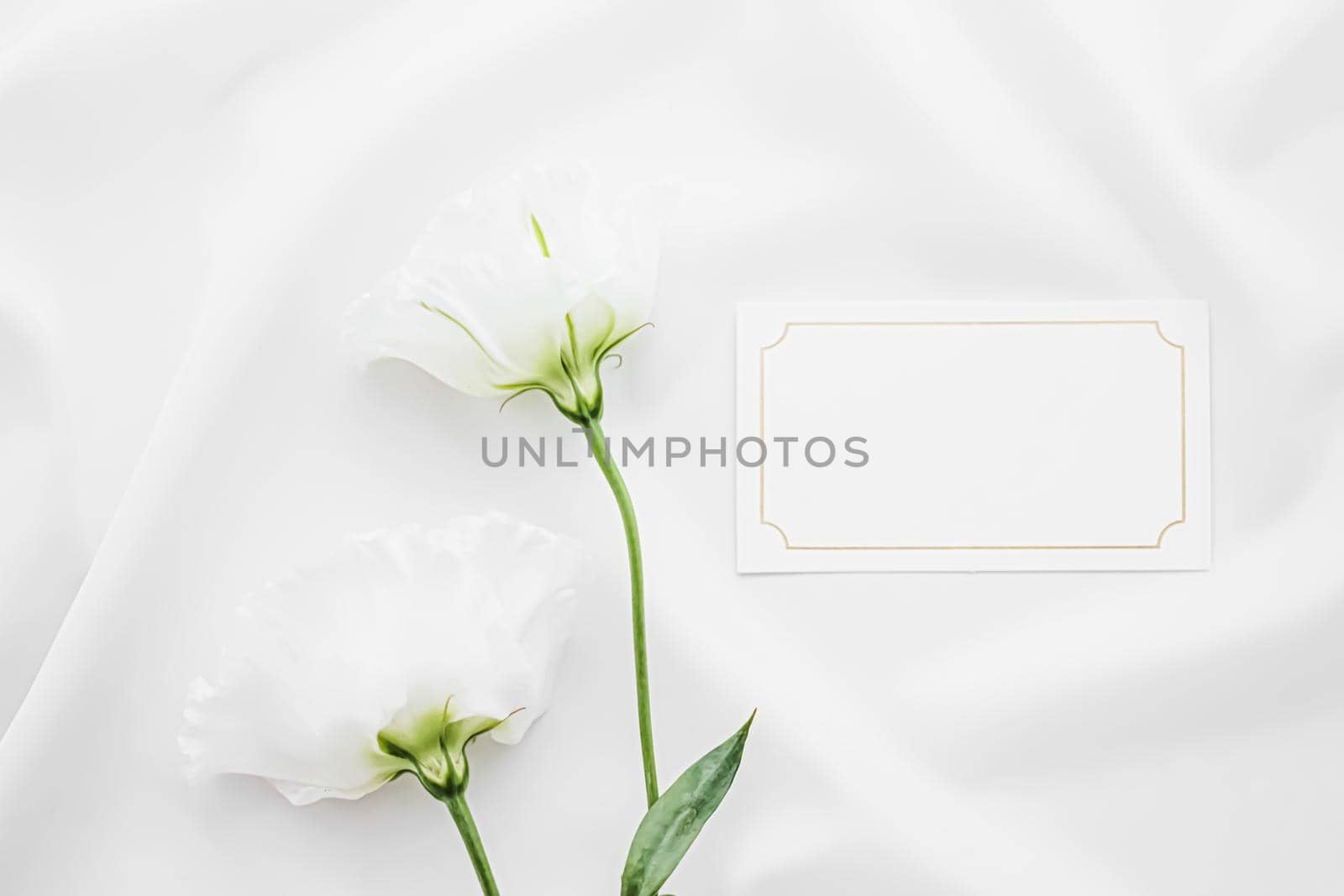 Wedding invitation or gift card and white rose flowers on silk fabric as bridal flatlay background, blank paper and holiday branding, flat lay design by Anneleven