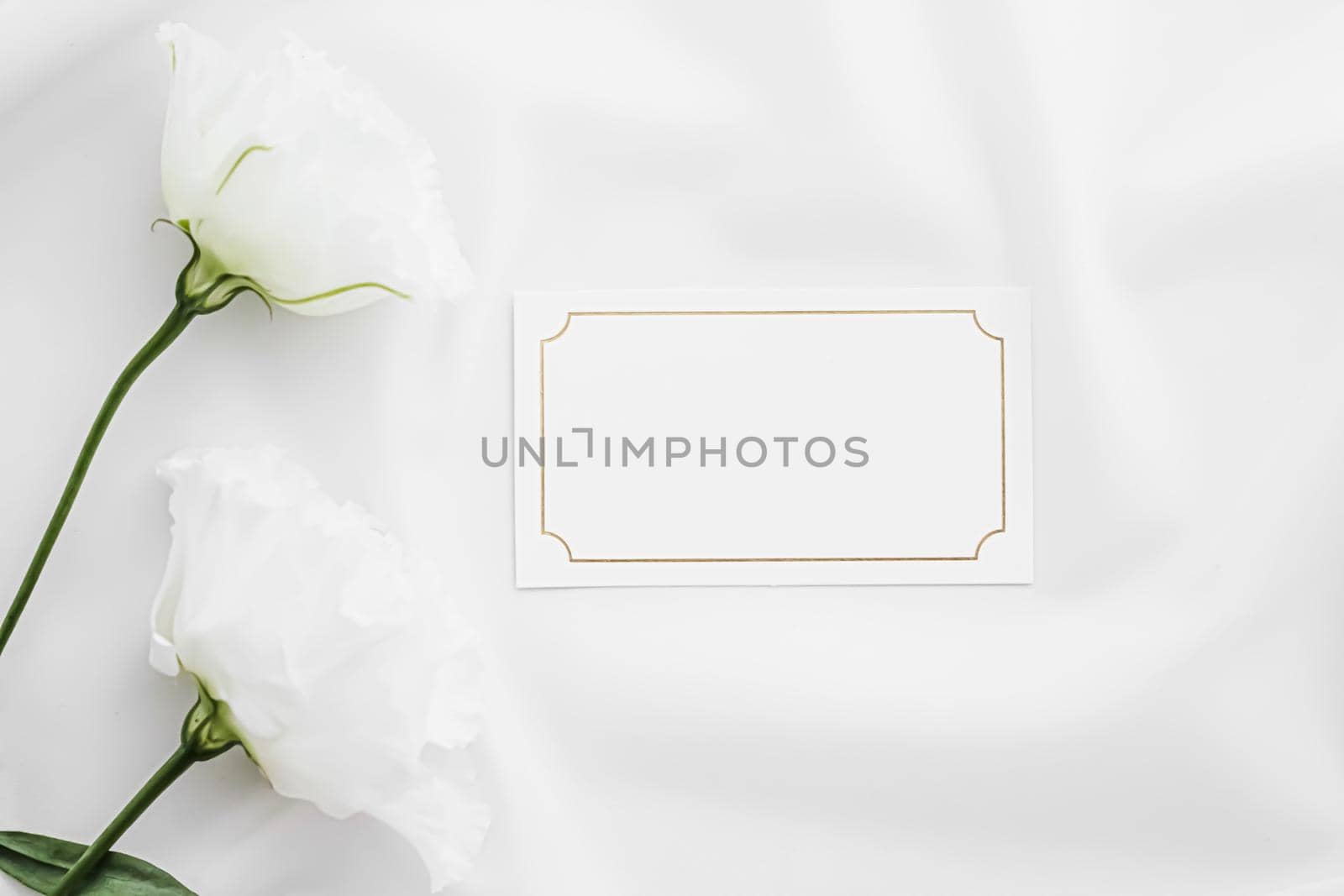 Wedding invitation or gift card and white rose flowers on silk fabric as bridal flatlay background, blank paper and holiday branding, flat lay design by Anneleven
