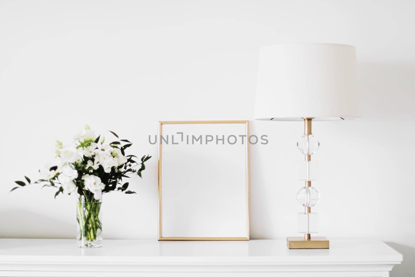 Golden vertical frame and bouquet of fresh flowers on white furniture, luxury home decor and design for mockup creation by Anneleven