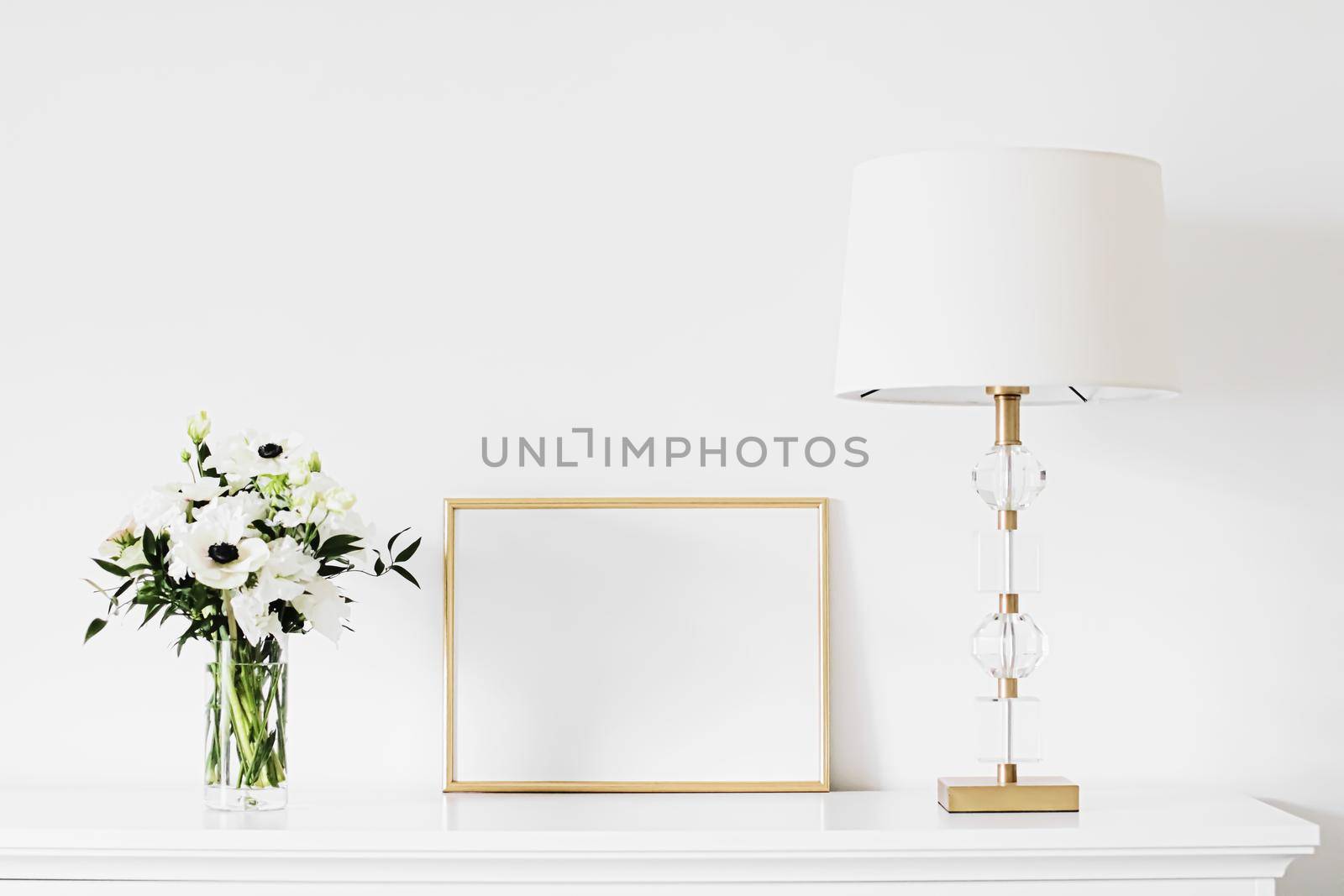 Golden horizontal frame and bouquet of fresh flowers on white furniture, luxury home decor and design for mockup creation by Anneleven