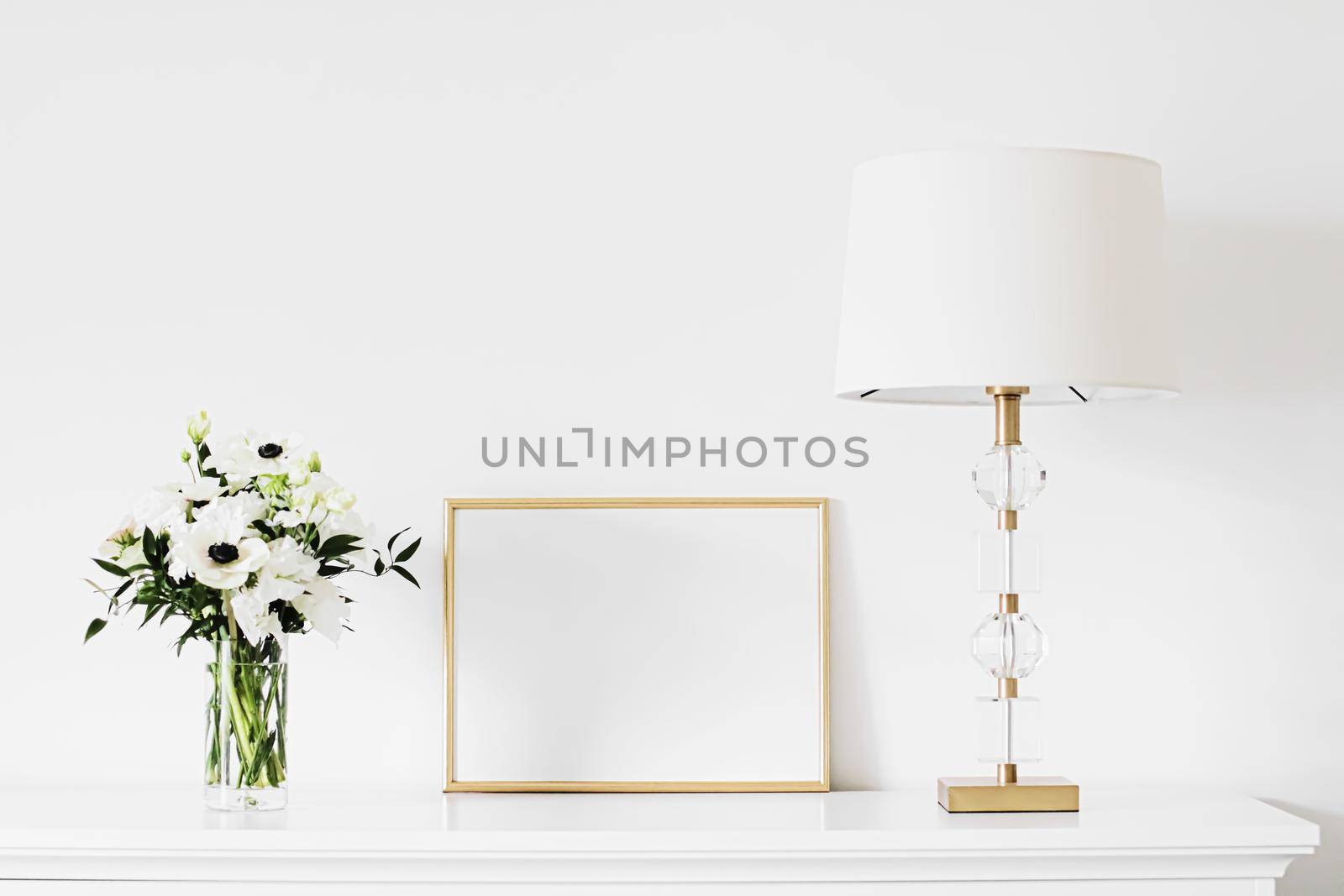 Golden horizontal frame and bouquet of fresh flowers on white furniture, luxury home decor and design for mockup creations