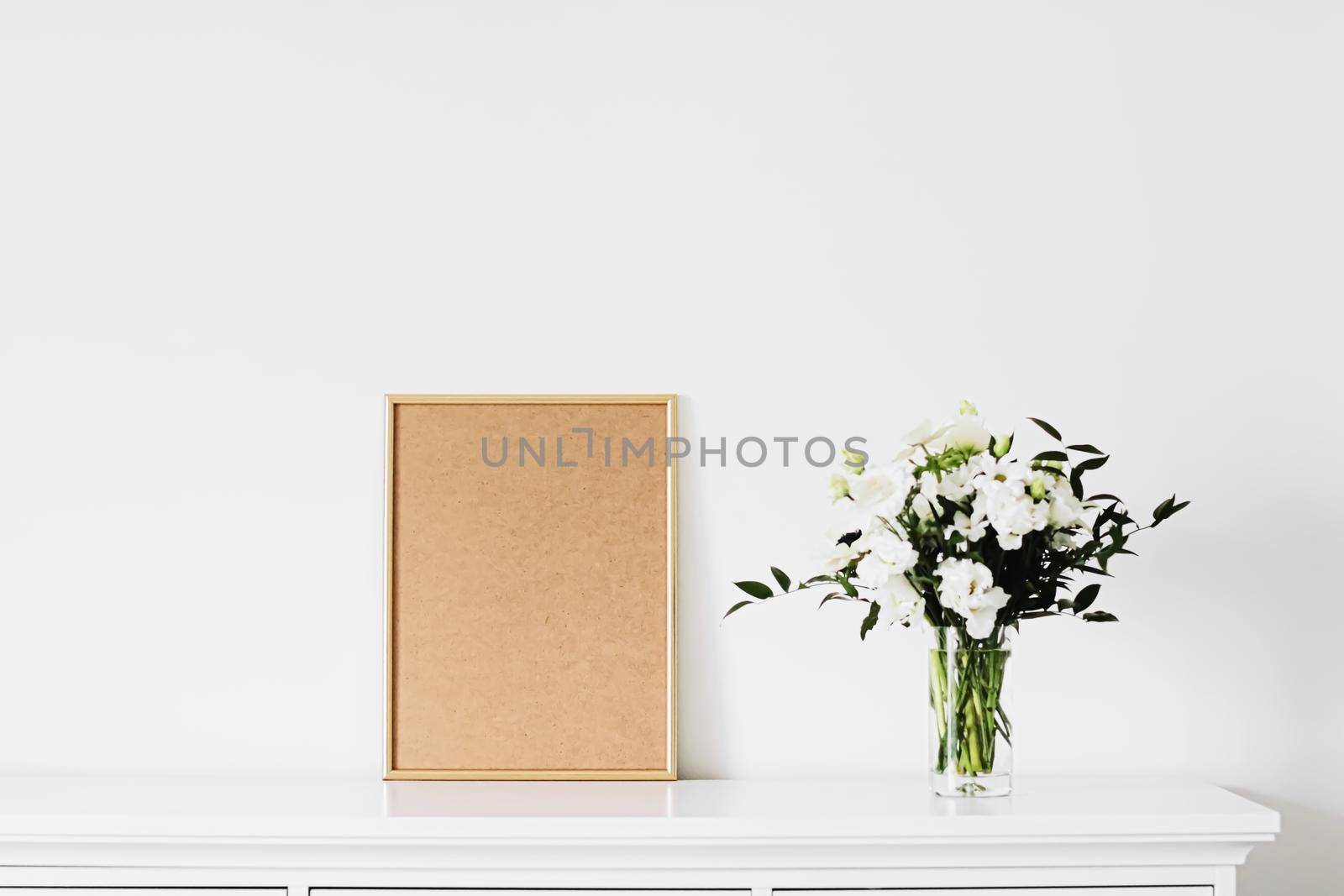 Golden vertical frame and bouquet of fresh flowers on white furniture, luxury home decor and design for mockup creation by Anneleven