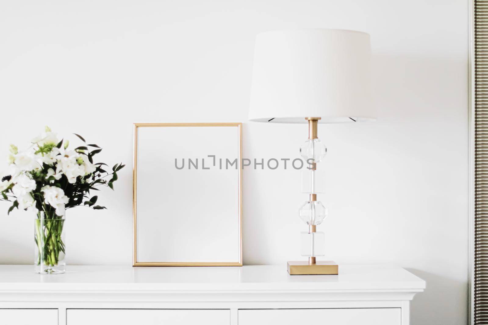 Golden vertical frame and bouquet of fresh flowers on white furniture, luxury home decor and design for mockup creation by Anneleven