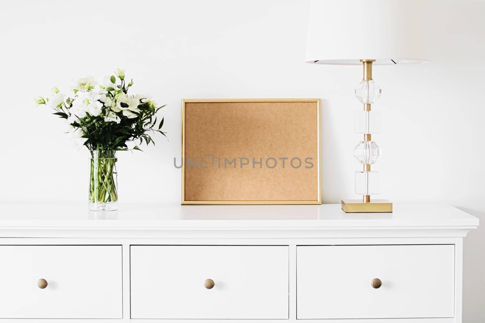 Golden horizontal frame and bouquet of fresh flowers on white furniture, luxury home decor and design for mockup creations
