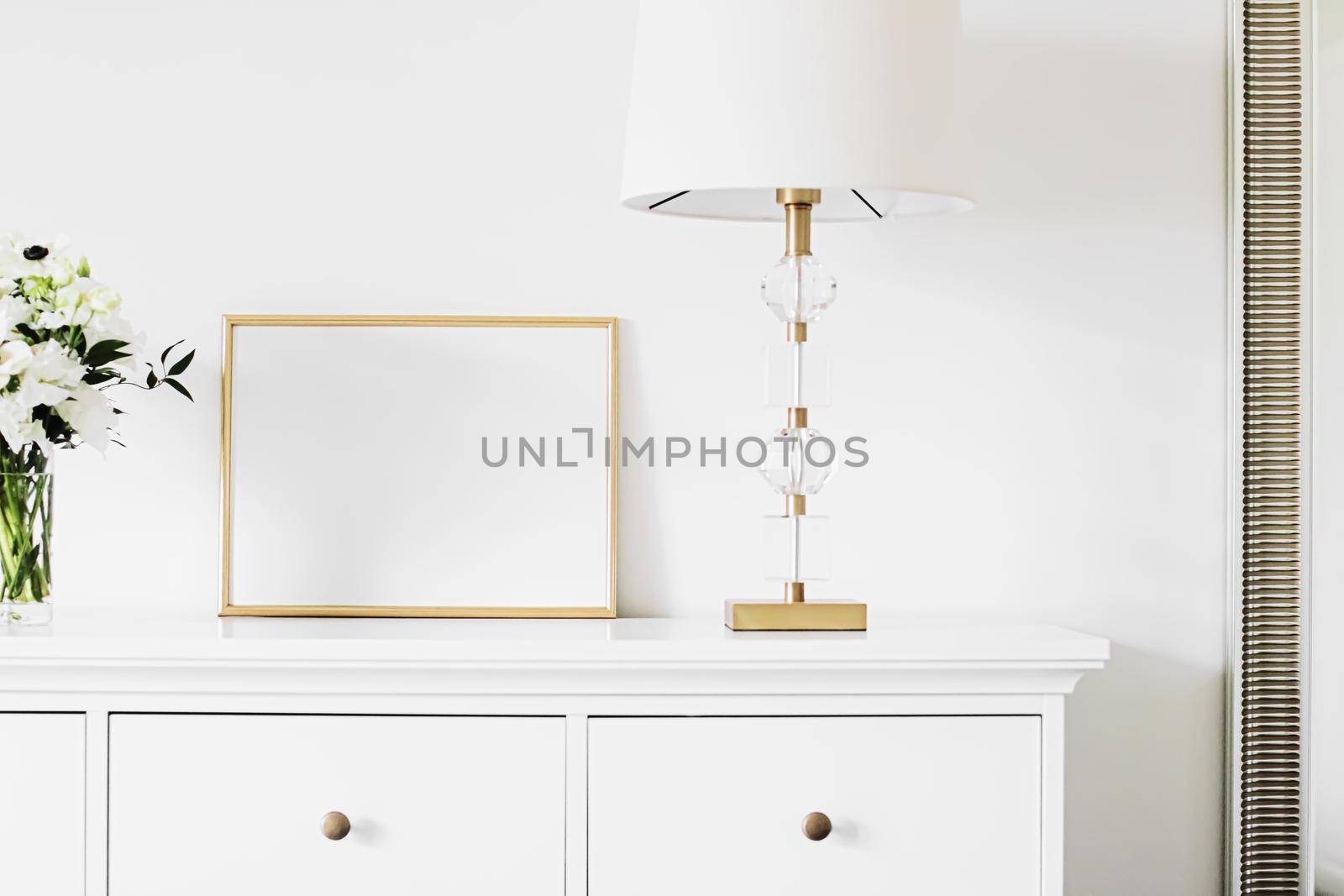 Golden horizontal frame and bouquet of fresh flowers on white furniture, luxury home decor and design for mockup creations