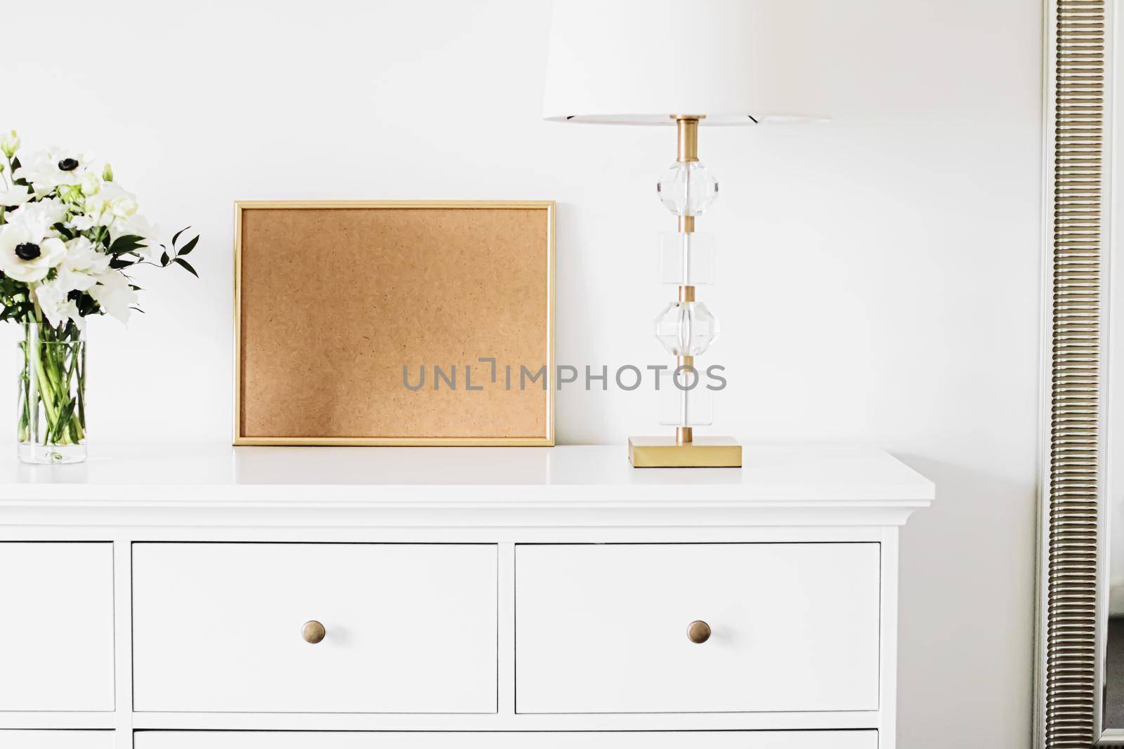 Golden horizontal frame and bouquet of fresh flowers on white furniture, luxury home decor and design for mockup creations