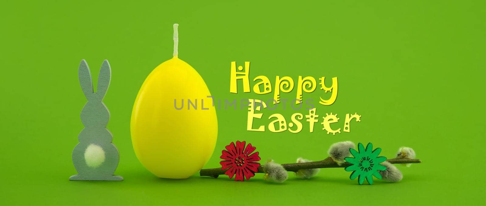 Easter holiday banner with yellow egg shaped candle, pussy willow branch and Easter Rabbit figure over a green background with text "Happy Easter"