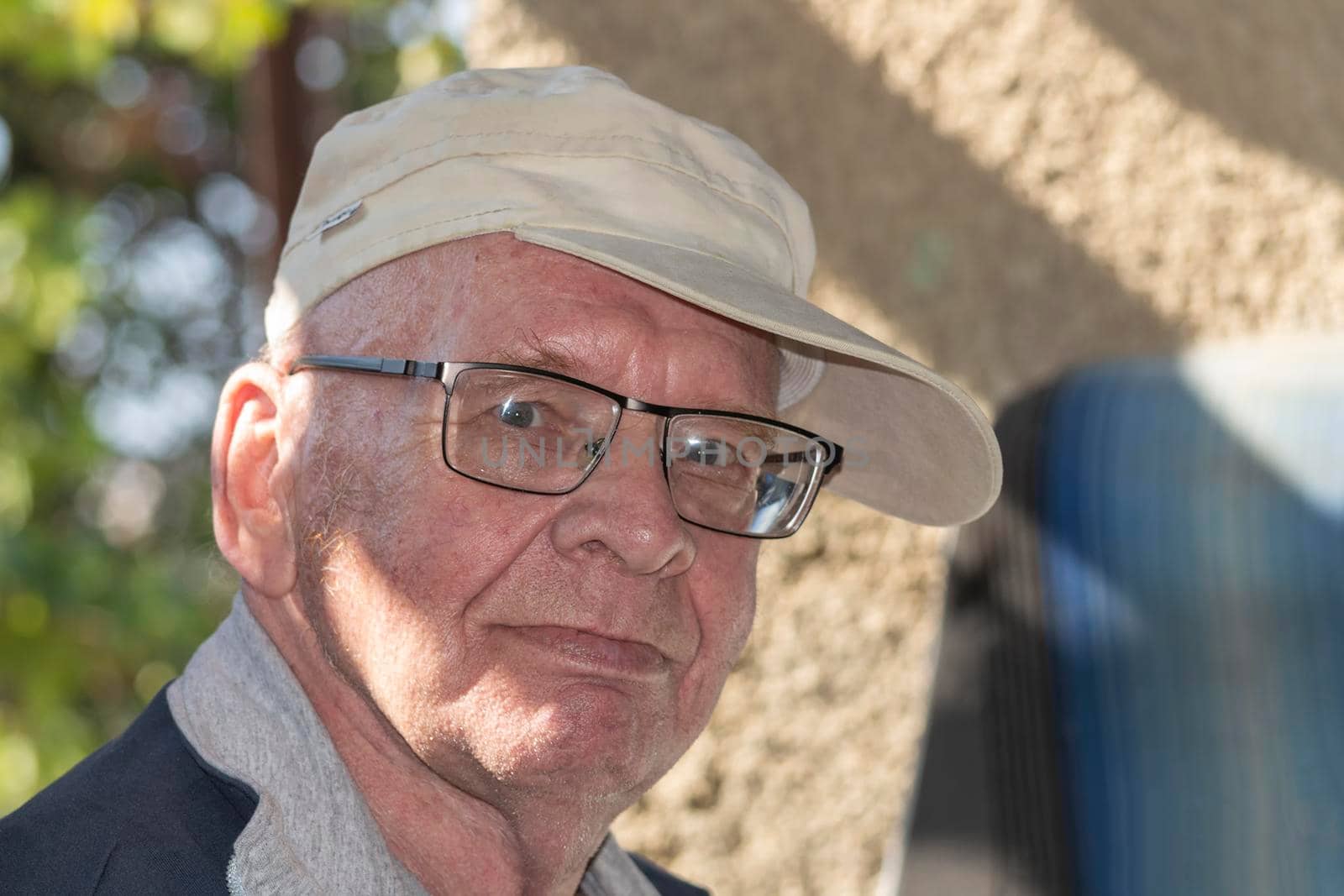 Old grandfather with glasses and brimmed straw hat. Looks into the camera on a sunny autumn day. by Essffes