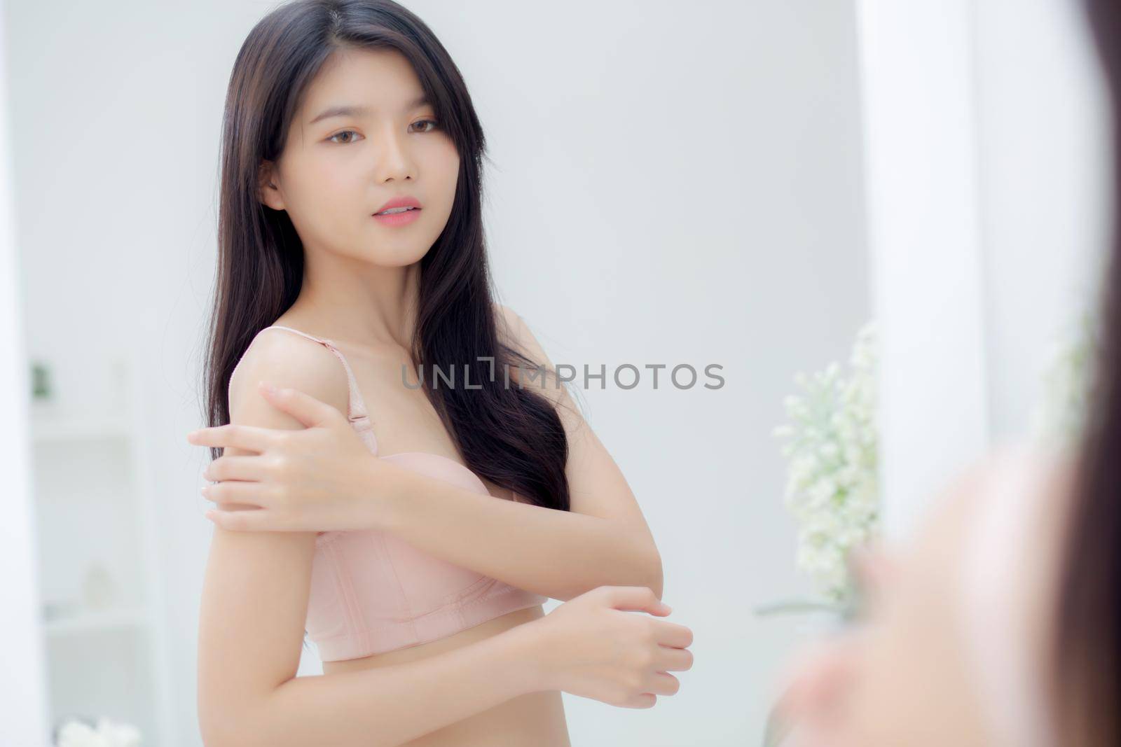 Beautiful sexy young asian woman look mirror applying cream on shoulder and message, beauty girl applying body lotion skin care for health and soft hydration, treatment and cosmetic with moisturizer.