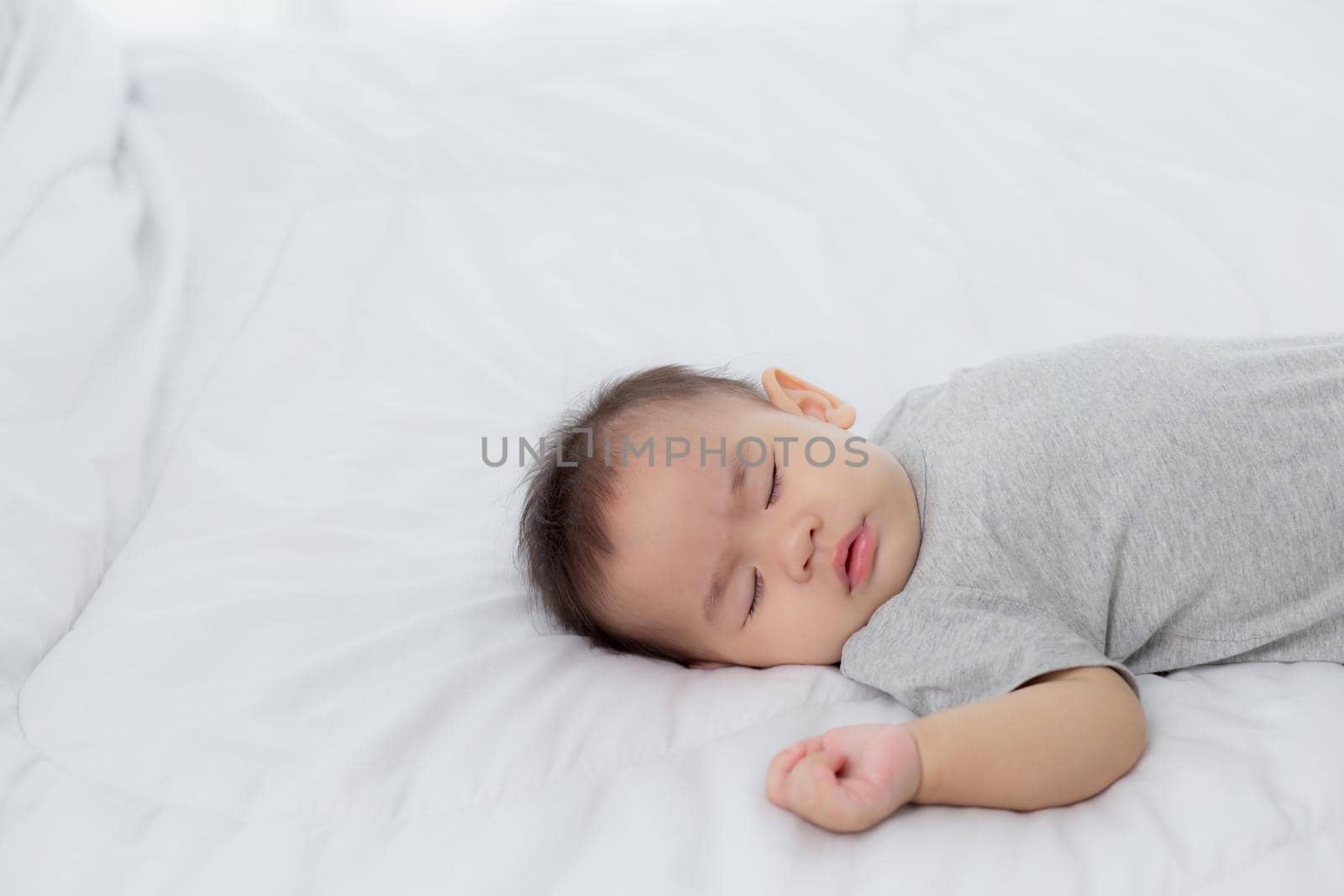 Portrait of asian little baby girl sleeping on bed in the bedroom at home, newborn napping with cozy and relax, infant innocence in bedtime, happy toddler cute, growth of child and emotion, indoors.