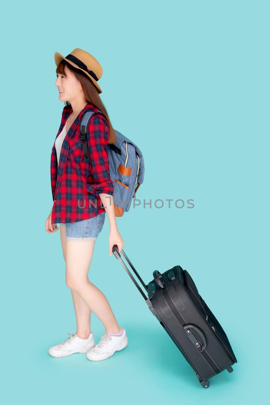 Beautiful young asian woman pulling suitcase isolated on blue background, asia girl having expression is cheerful holding luggage walking in vacation with excited, journey and travel concept. by nnudoo