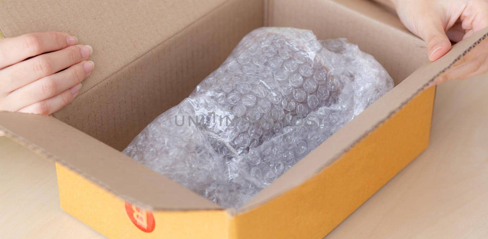 Closeup hand of woman opening parcel box with check product at home, female unpack with knife, delivery and shipping, shipment and express for shop, online shopping store and service concept.