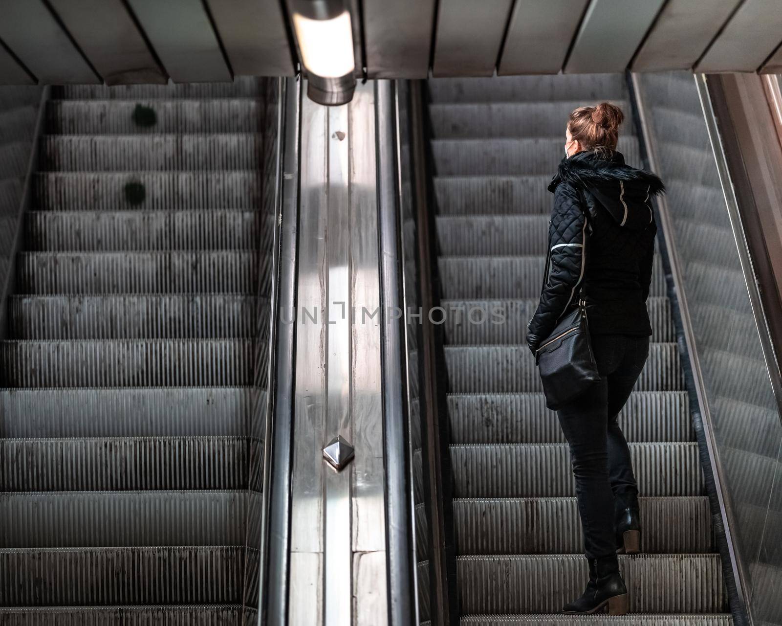 woman goes on an escalator in the subway by Edophoto