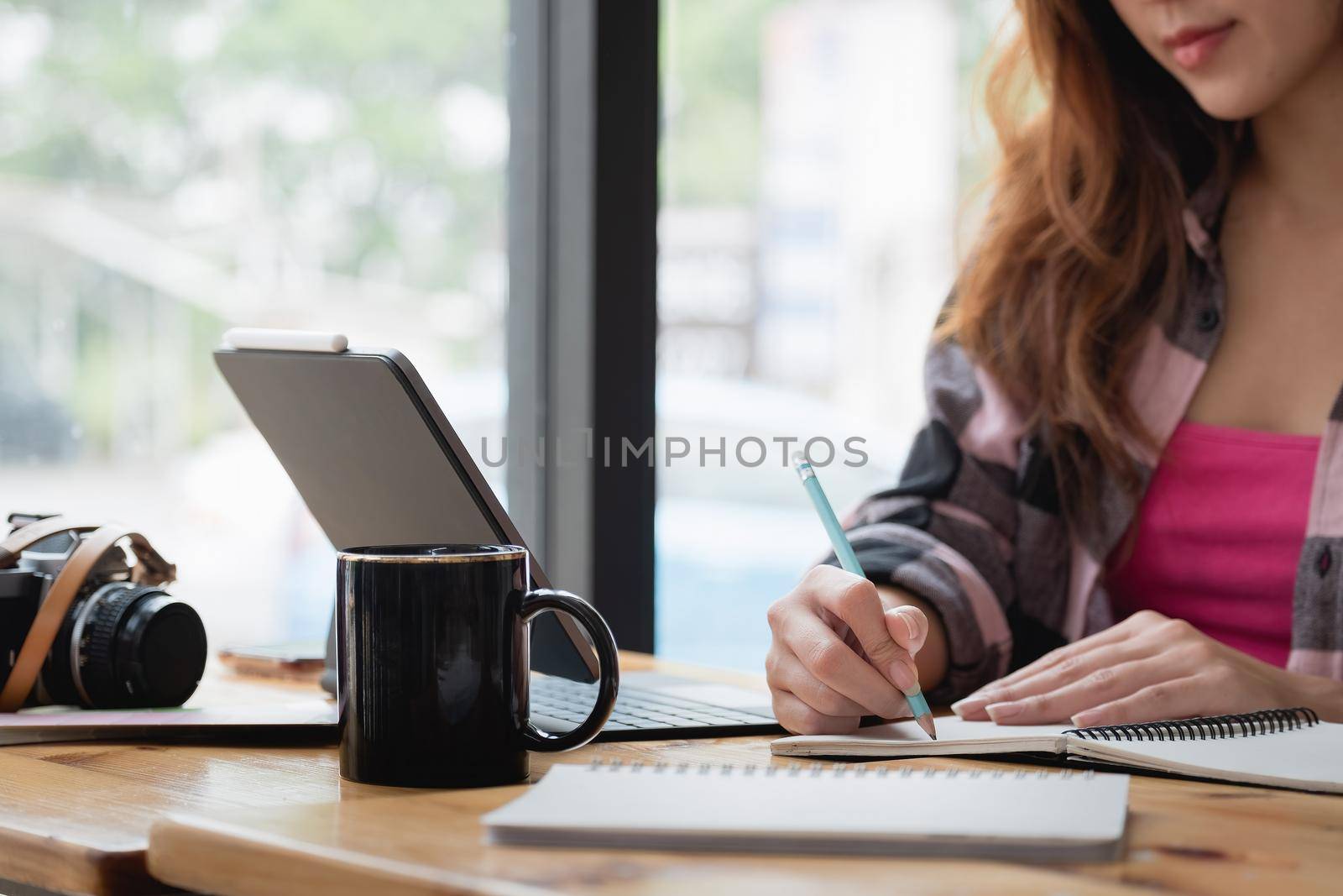 Student study online with teacher, happy young woman learn language listen lecture watch webinar write notes look at laptop sit in cafe, distant education. by nateemee