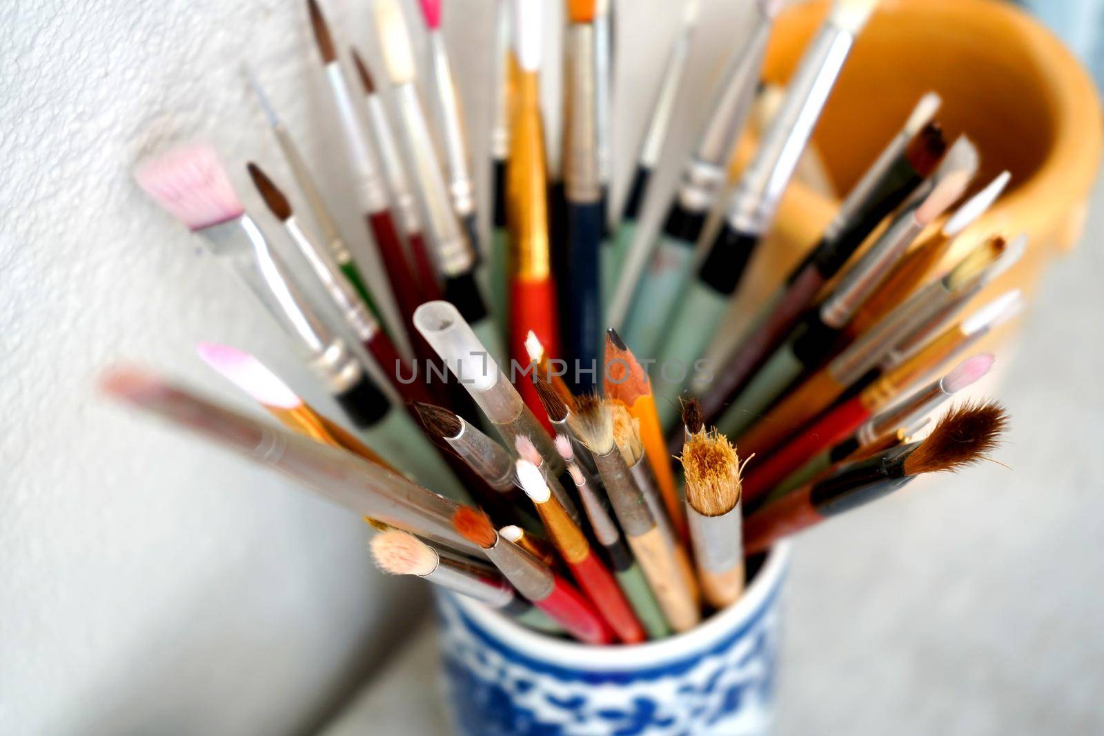 Detail of paint brushes and bright paint in an artist’s studio by fivepointsix