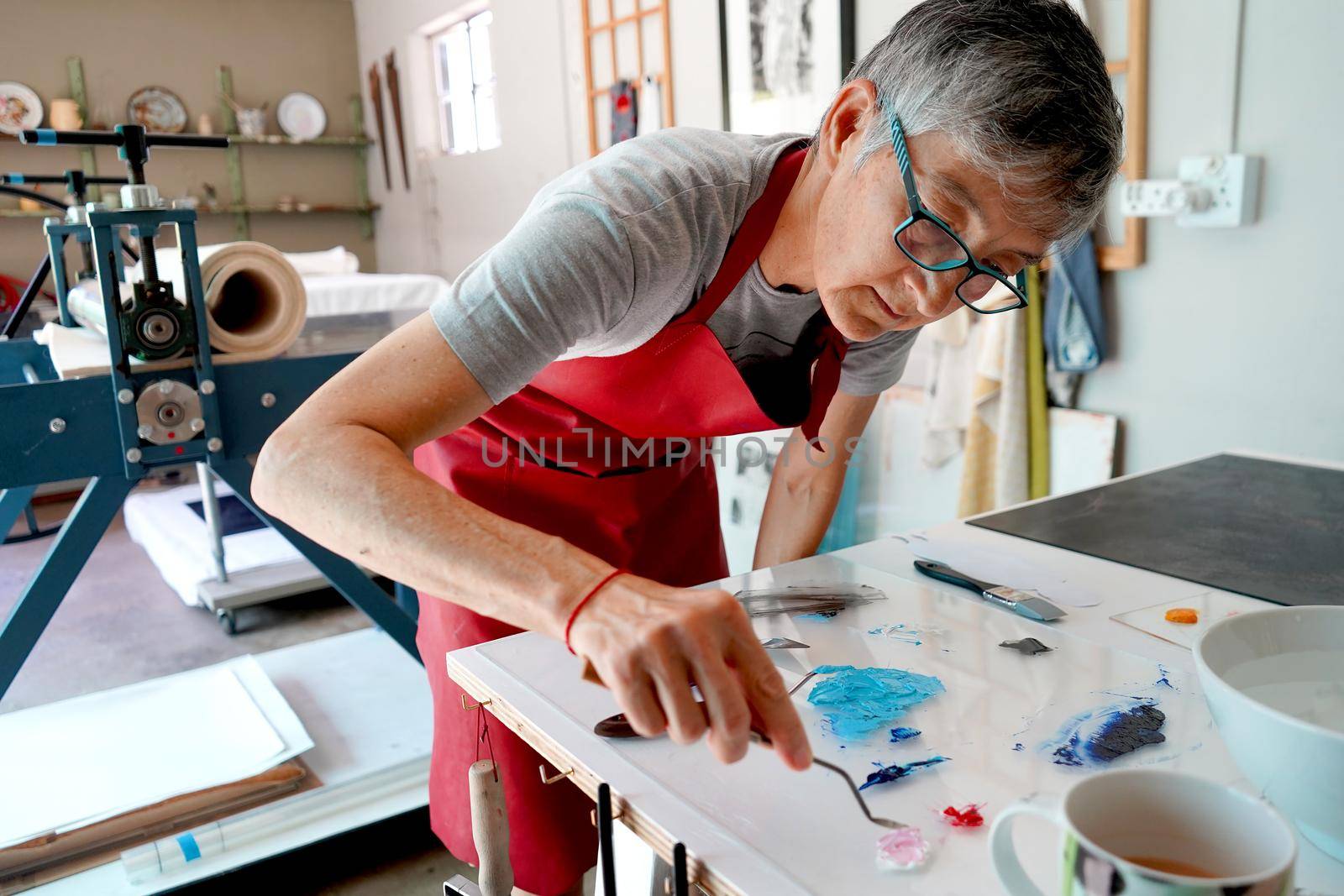 Artist working in her studio wiht paintbrushes and a print by fivepointsix